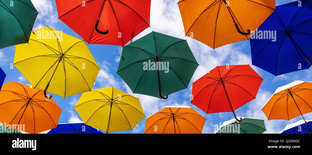 Bunte Regenschirme hängen vor blauem Himmel Hintergrund. Banner Stockfoto