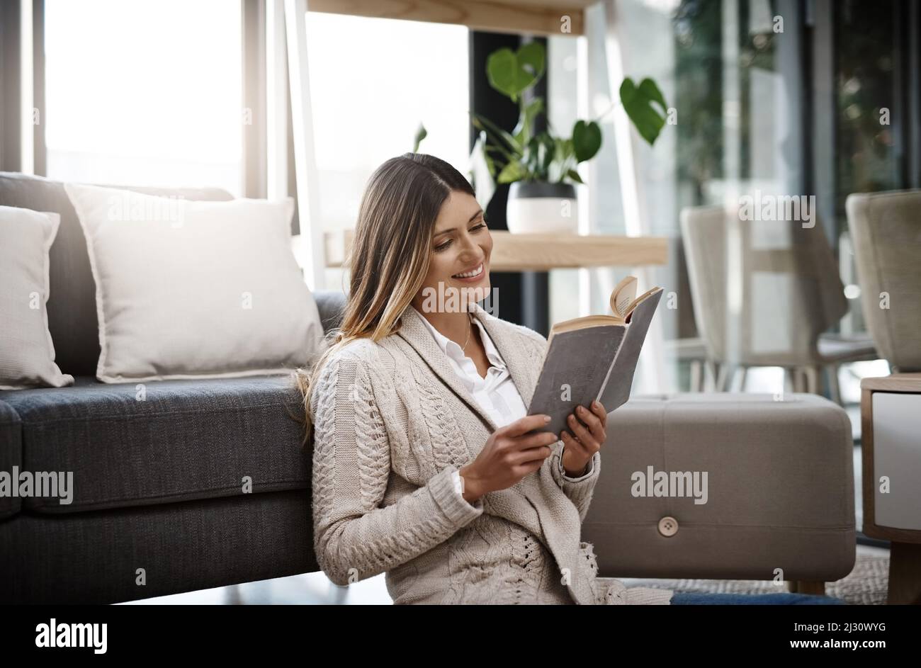 Lesen ist bei weitem das erfolgreichste Streben nach Glück. Eine kurze Aufnahme einer schönen jungen Frau, die ein Buch liest, während sie sich zu Hause entspannt. Stockfoto