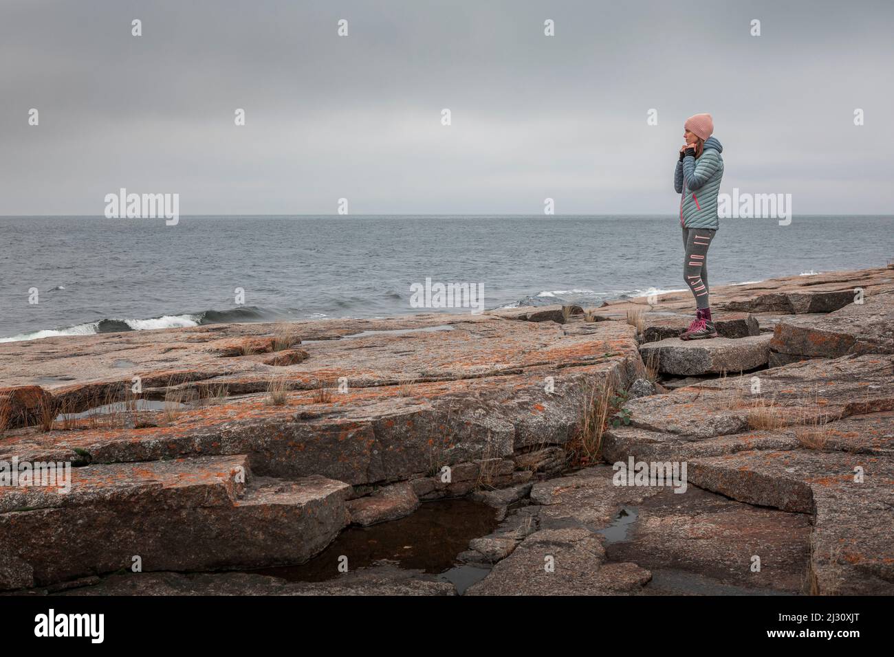 Frau an der felsigen Küste von Rotsidan im Osten Schwedens Stockfoto