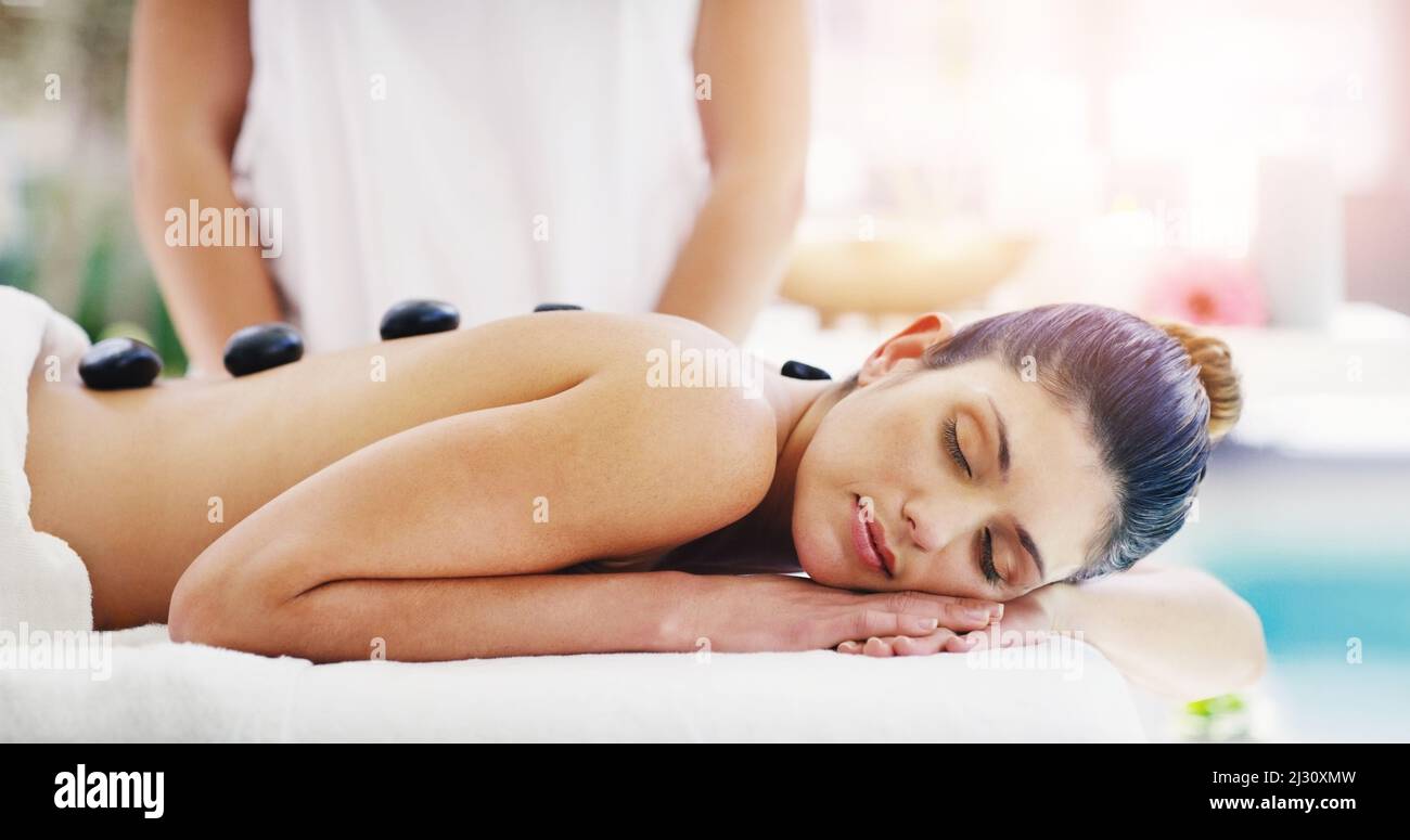 Diese Steine werden all eure Spannungen ausarbeiten. Aufnahme einer jungen Frau, die in einem Spa eine Hot-Stone-Massage bekommt. Stockfoto