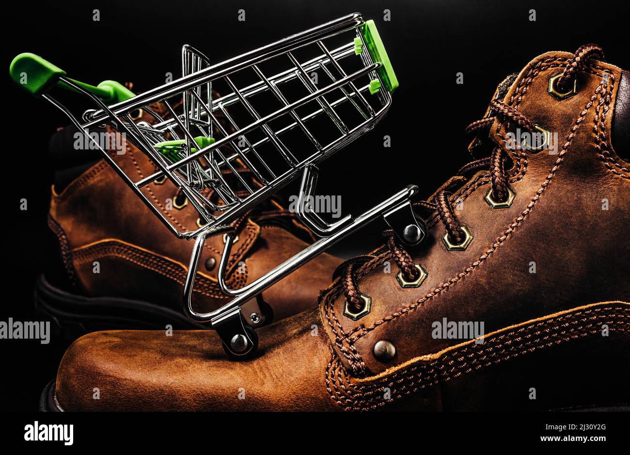 Foto von braunen Wildleder Schuhe stehen auf schwarzem Hintergrund mit kleinen Warenkorb darauf. Stockfoto