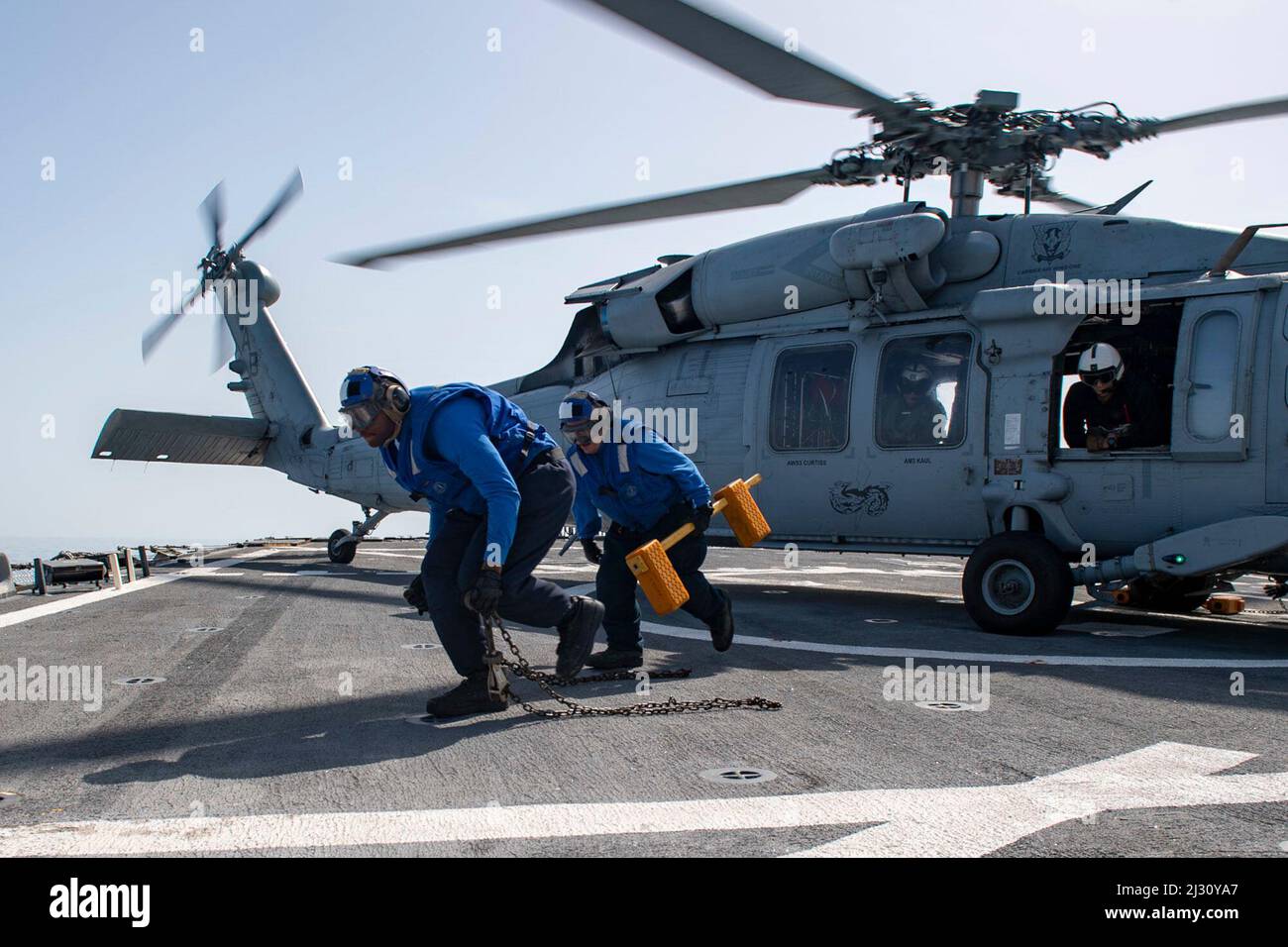 220329-N-HG846-1066 ÄGÄISCHES MEER (29. März 2022) – Mate Seaman Auntarrion Coutee des Bootswains, links, aus Houston, Texas, Und Boatswains Mate 2. Klasse Devin ingle, rechts, aus Bloomfield, Iowa, entfernen Keile und Ketten von einem MH-60s Sea Hawk Hubschrauber, der den „Dragoslayers“ des Helicopter Sea Combat Squadron (HSC) 11 zugewiesen wurde, auf dem Flugdeck an Bord des Arleigh Burke-Klasse Lenkraketen-Zerstörers USS Mitscher (DDG 57), 29. März 2022. Mitscher ist derzeit bei der Harry S. Truman Carrier Strike Group im Einsatzgebiet der Sechsten Flotte der USA zur Unterstützung der USA, der Alliierten und des Partners i im Einsatz Stockfoto