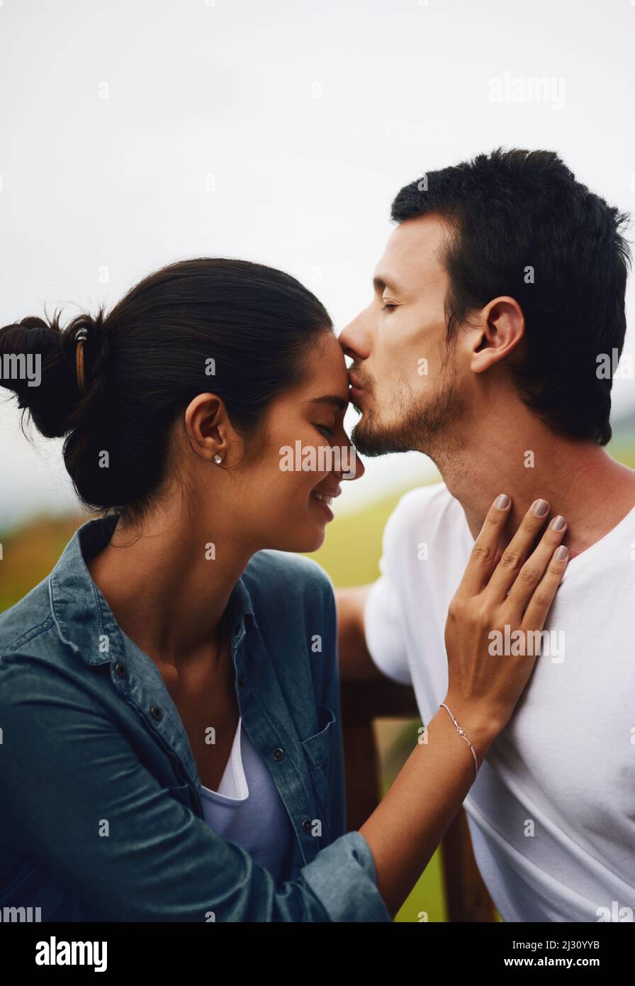Stirnküsse, das schönste Gefühl der Welt. Aufnahme eines liebevollen jungen Paares, das einen romantischen Tag im Park verbringt. Stockfoto