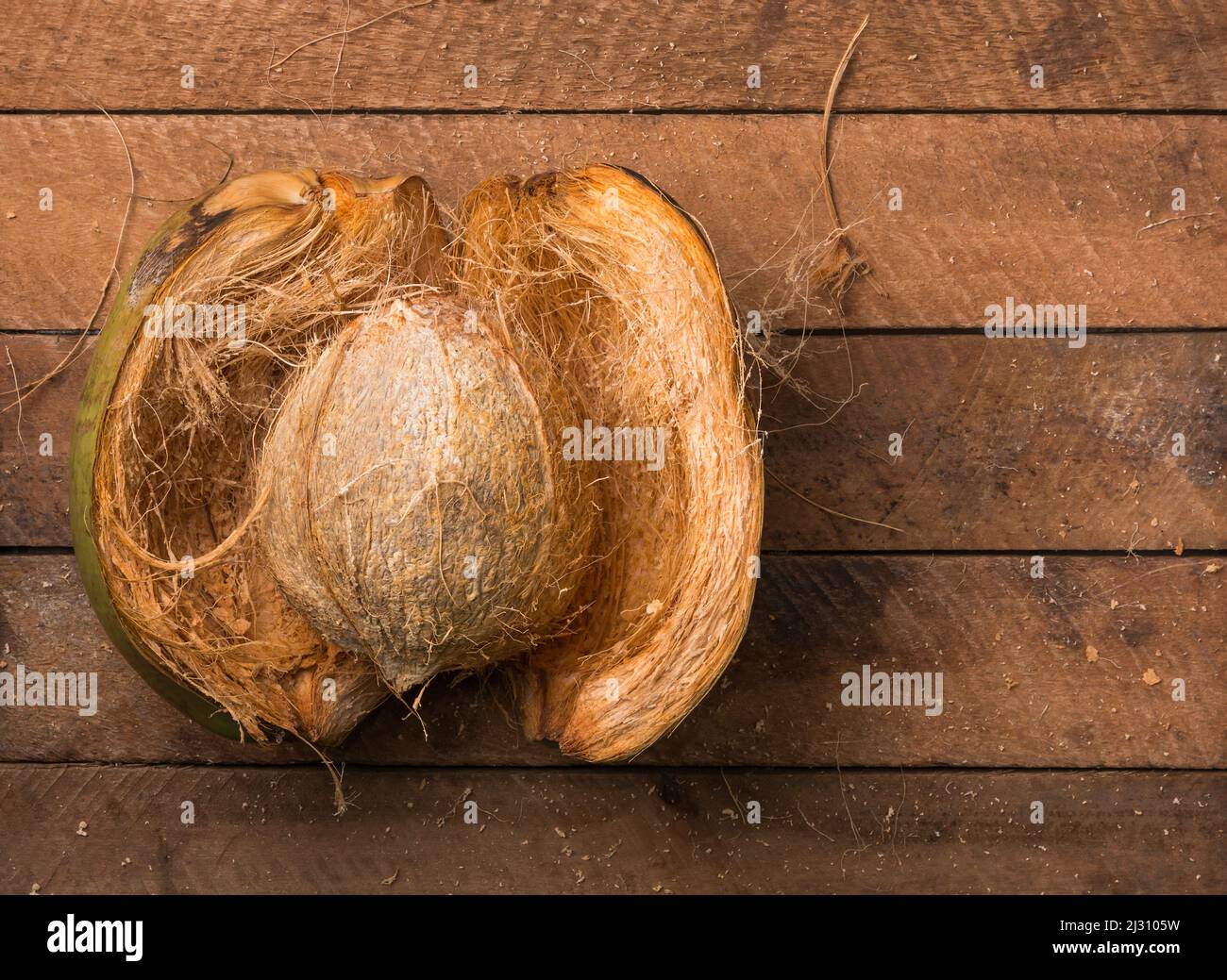 Offene Kokosnuss mit Schale, gesunde tropische Früchte auf einer hölzernen Tischplatte, von oben mit Kopierraum aufgenommen Stockfoto