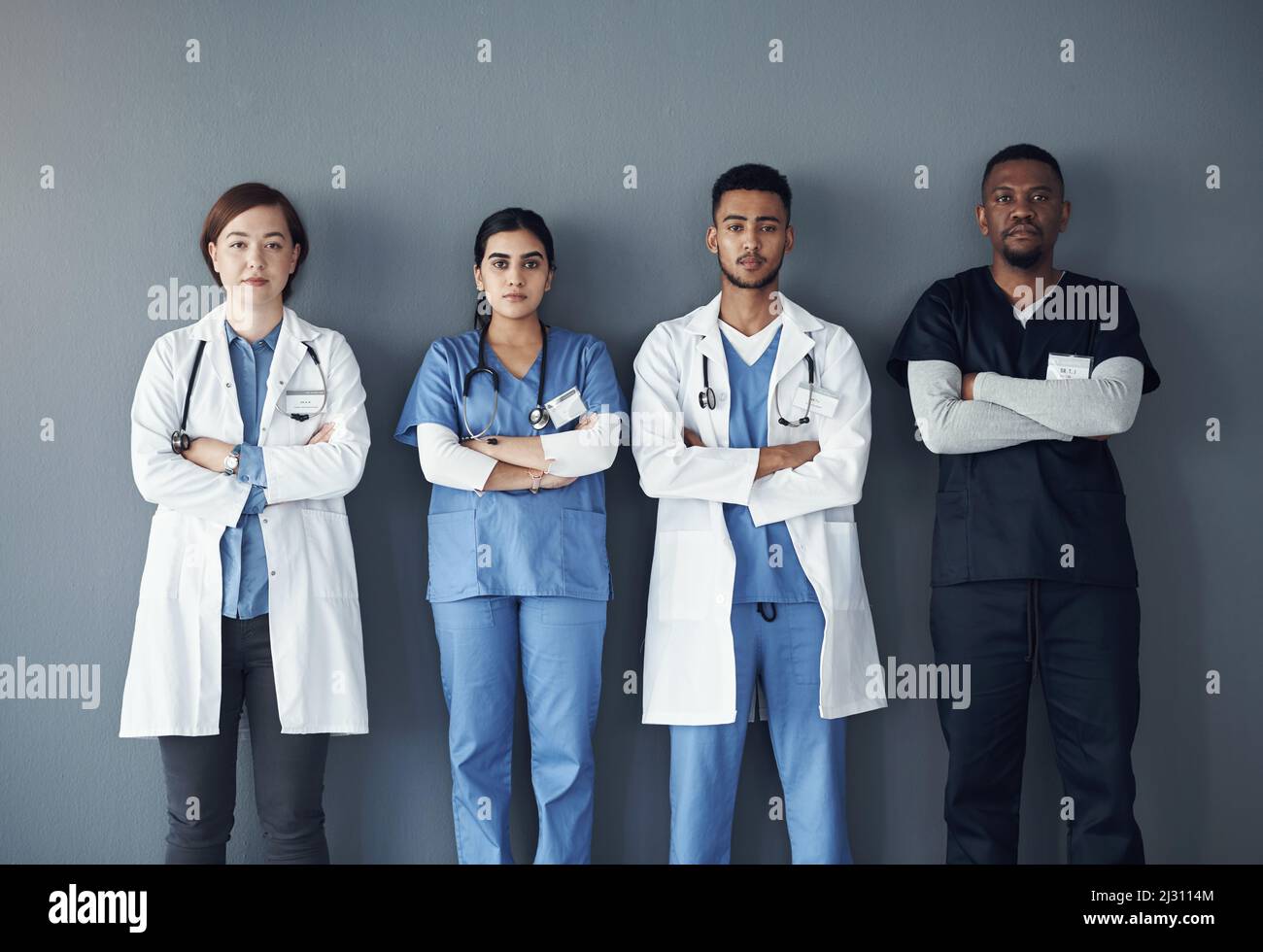 Als Pflegekraft erleben Sie jeden Tag selbstlose Handlungen. Aufnahme einer Gruppe von Ärzten, die bei der Arbeit vor einem grauen Hintergrund stehen. Stockfoto