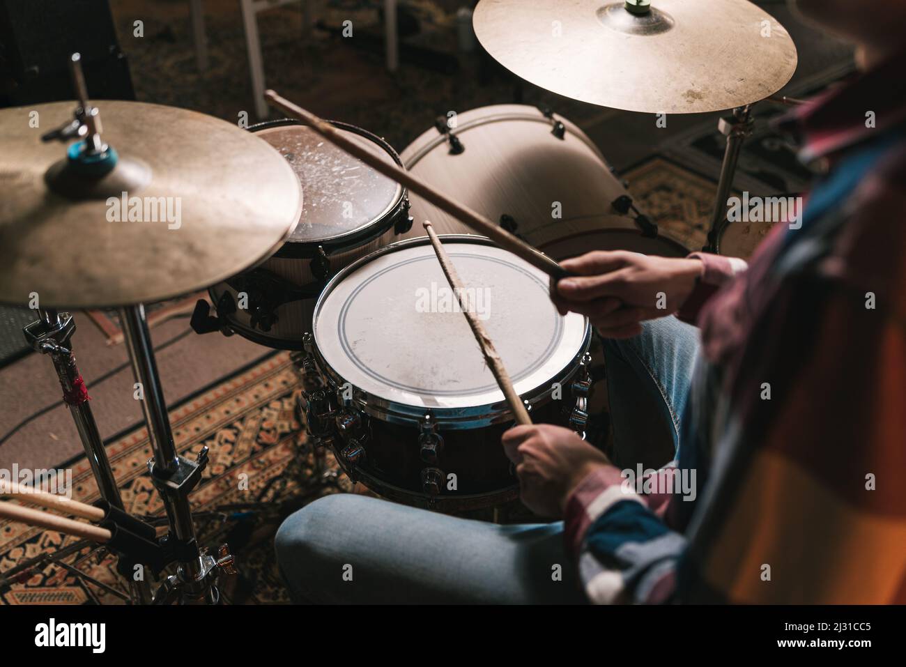 High Angle of Crop anonymer männlicher Musiker, der während der Probe Rhythmus auf dem Schlagzeug spielt Stockfoto