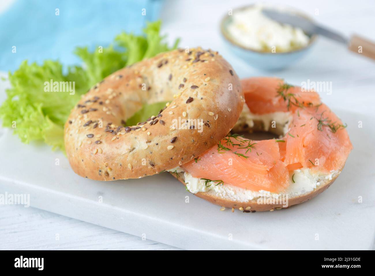 Frisches Multigrain-Bagel-Brötchen mit Frischkäse, Lachsscheiben, Dill und grünem Salat, gesundes Lebensmittelkonzept Stockfoto