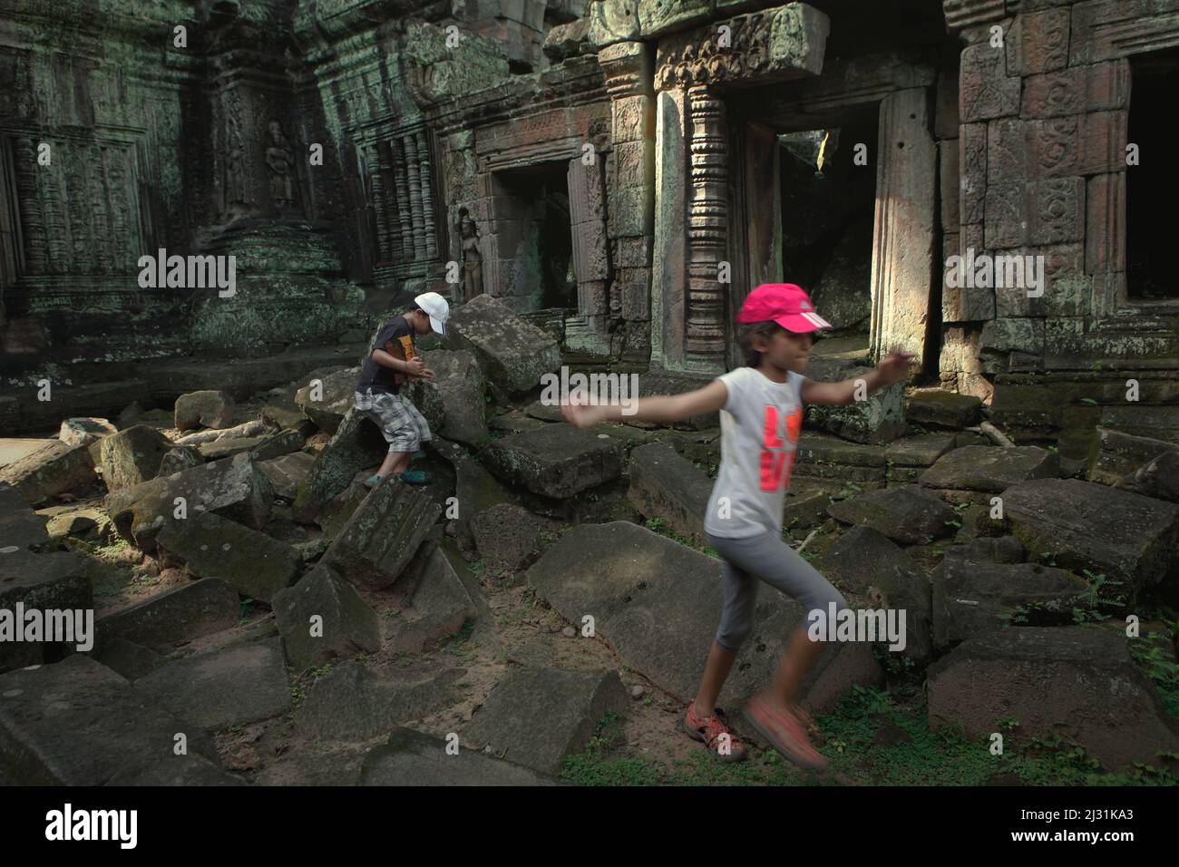 Kinder spielen zwischen den Ruinen des Ta Prohm Tempels in Siem Reap, Kambodscha. Einst als Drehort für einen Hollywood-Film von 2001 verwendet Lara Croft: Tomb Raider mit Angelina Jolie und vor allem bekannt für seine riesigen Wurzeln aus wilden Bäumen, die tief zwischen den Steinen verwurzelt sind, war Ta Prohm ein Kloster für Studenten des Mahayana-Buddhismus, bevor es verlassen und für Hunderte von Jahren vergessen wurde. Stockfoto