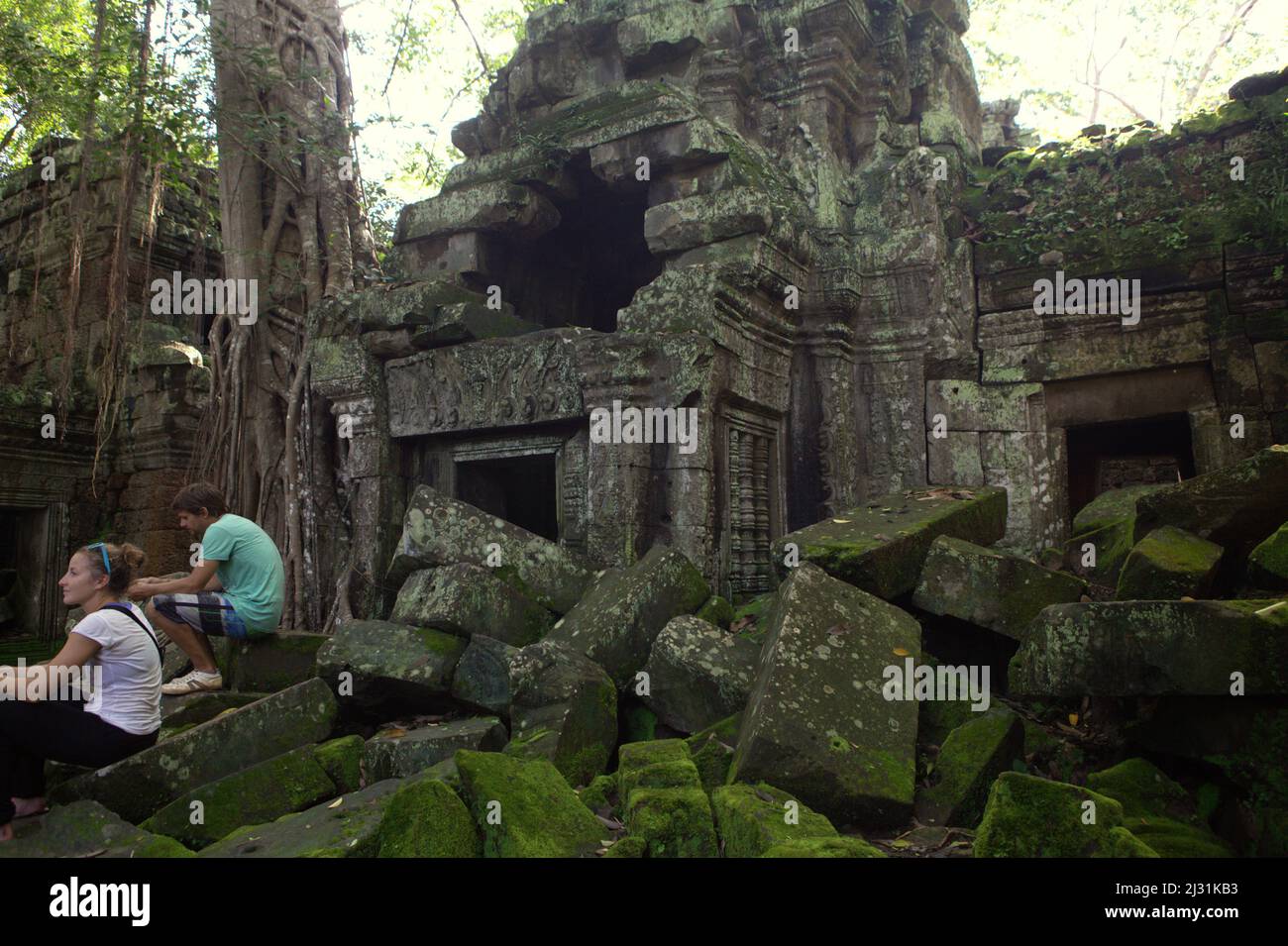 Touristen erholen sich auf den Ruinen des Ta Prohm Tempels in Siem Reap, Kambodscha. Einst als Drehort für einen Hollywood-Film von 2001 verwendet Lara Croft: Tomb Raider mit Angelina Jolie und vor allem bekannt für seine riesigen Wurzeln aus wilden Bäumen, die tief zwischen den Steinen verwurzelt sind, war Ta Prohm ein Kloster für Studenten des Mahayana-Buddhismus, bevor es verlassen und für Hunderte von Jahren vergessen wurde. Stockfoto