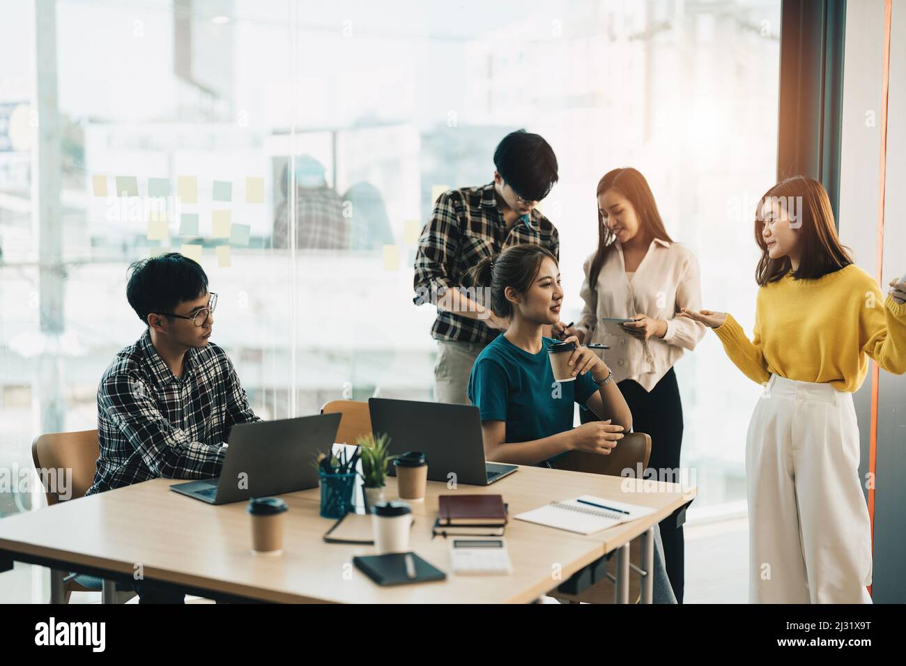 Gruppe junger kreativer asiatischer Menschen, die Brainstorming-Treffen mit Kollegen im Vorstandszimmer machen, um das Projekt zu diskutieren. Frau, die am Whiteboard steht, geben Stockfoto