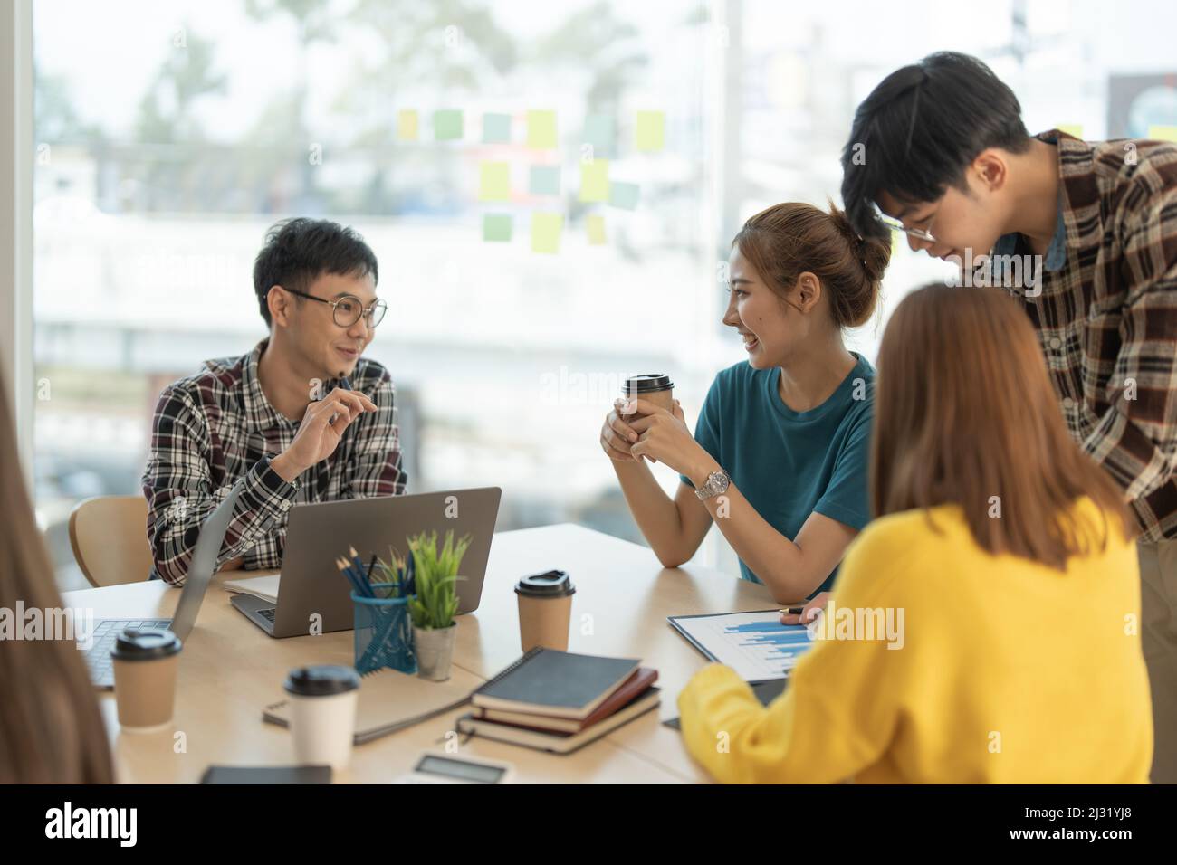 Gruppe von asiatischen Unternehmen diskutieren Projekt auf Laptop Kollegen, arbeiten zusammen in Paaren am gemeinsamen Arbeitsplatz, Analyse elektronischer Dokumente. Stockfoto