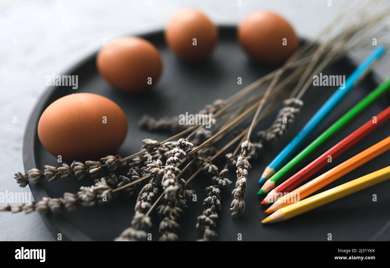 Mehrfarbige Farben und Pinsel auf dem Teller mit Eiern. Färbeeier für osterferien Konzept. Stockfoto