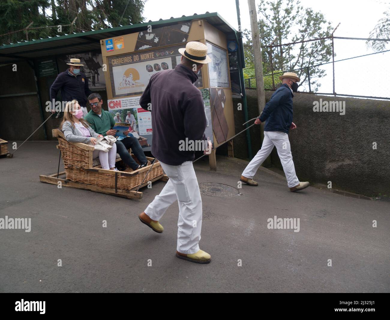 Männer steuern Rodel mit männlichen und weiblichen Touristen an Ort und Stelle zu starten Weidenfahrt auf der Straße nach Livramento Monte Funachal Madeira Portugal EU Stockfoto