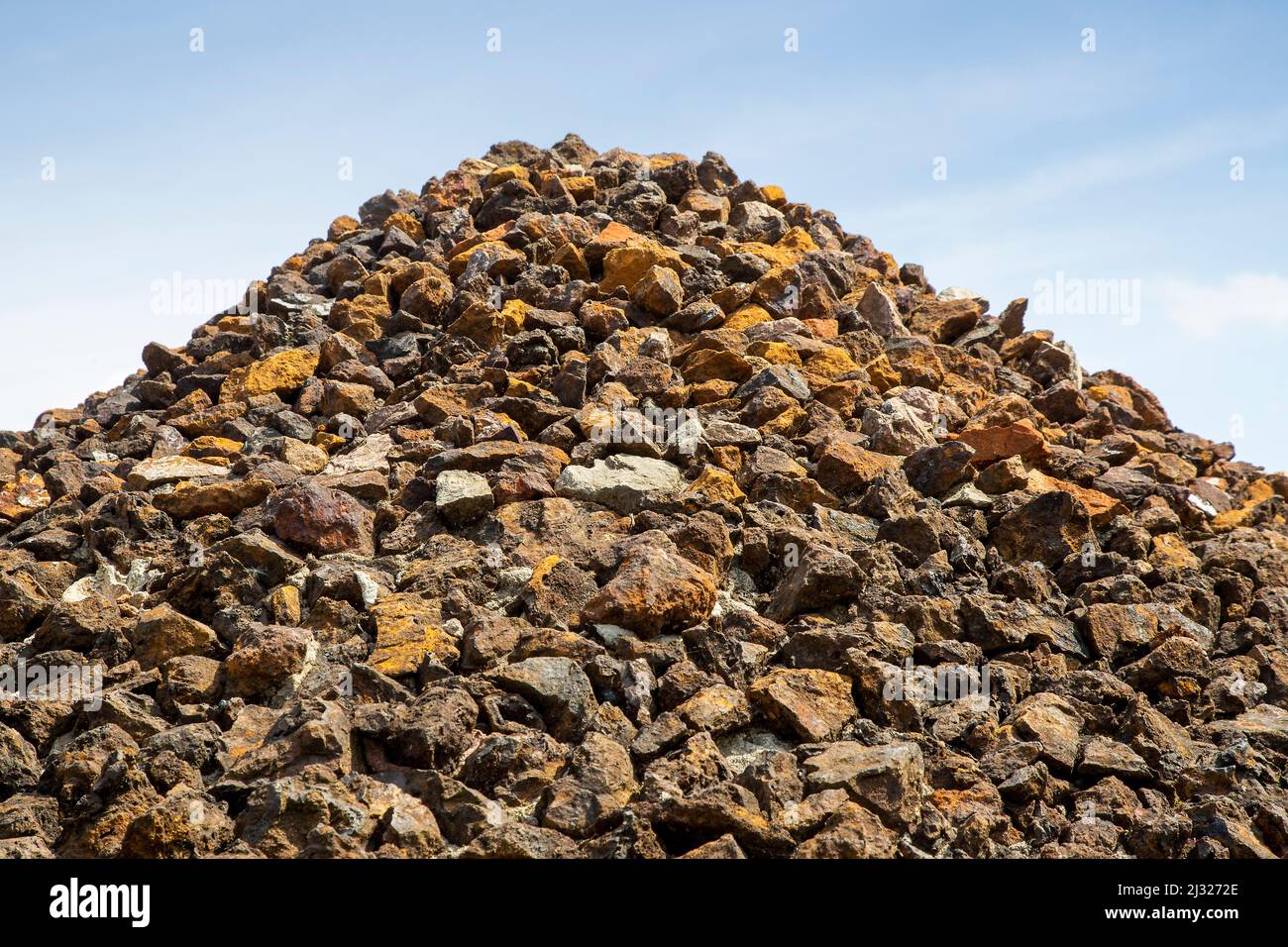Spanien, die Berge rund um die Stadt Bilba haben aufgrund des Eisenbergbaus wirtschaftliches Wachstum gebracht. Ein Haufen Eisenerz als Denkmal, gleich daneben Stockfoto