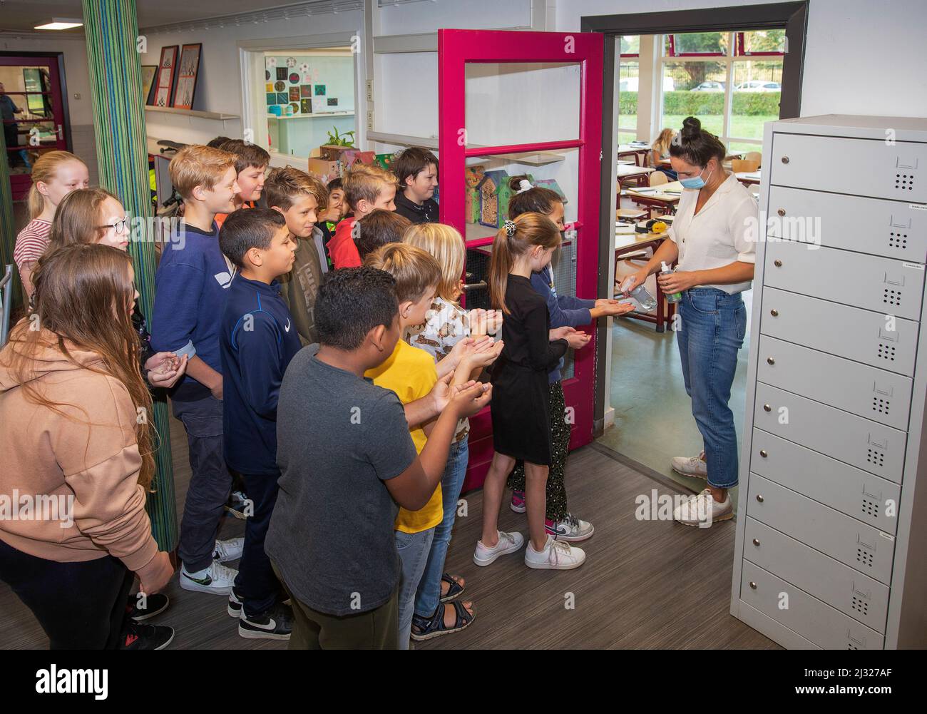 Niederlande, 8. Grundschulkinder werden von der Lehrerin mit den Händen desinfiziert, bevor sie in den Klassenzimmer gehen. Um die Hände zu desinfizieren ich Stockfoto