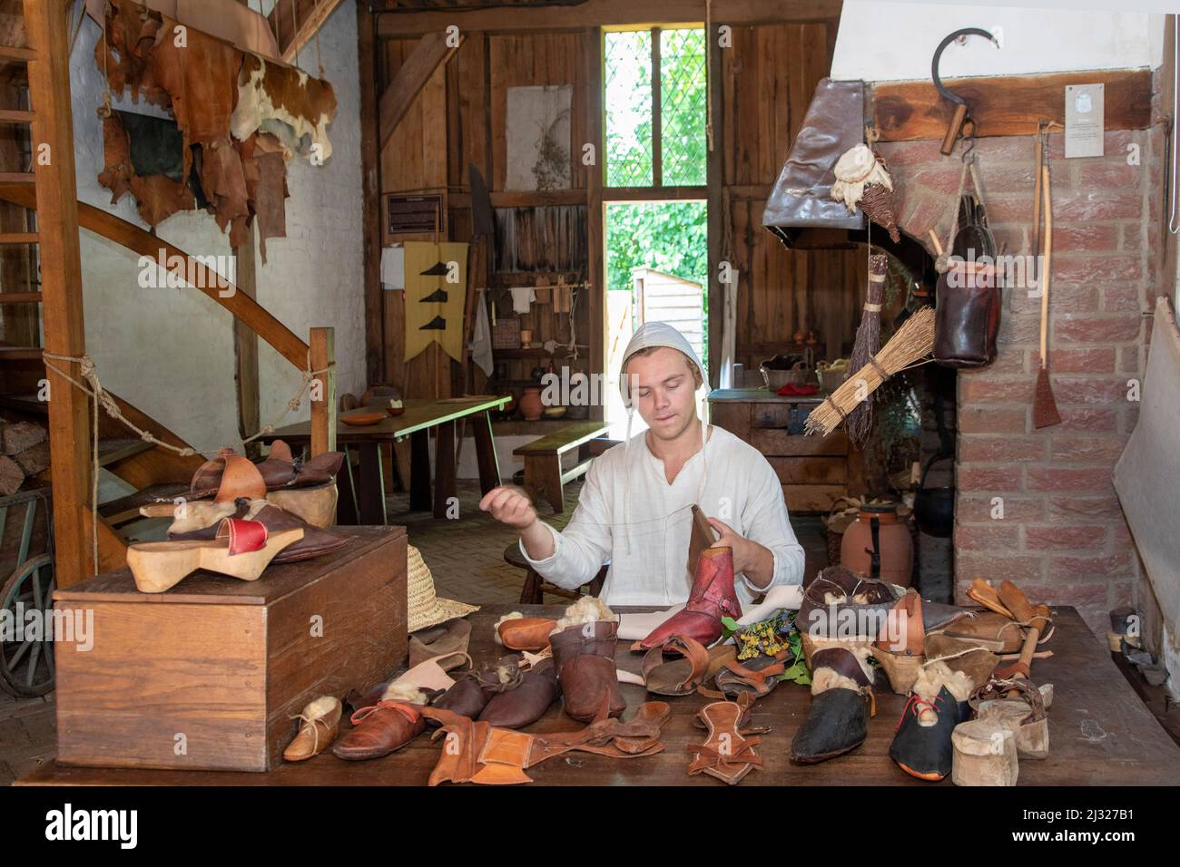 Niederlande, Schuhmacher in seinem Laden im Mittelalter. Der Archeon Park zeigt eine kleine mittelalterliche Stadt, in der der Laden zu sehen ist. Stockfoto