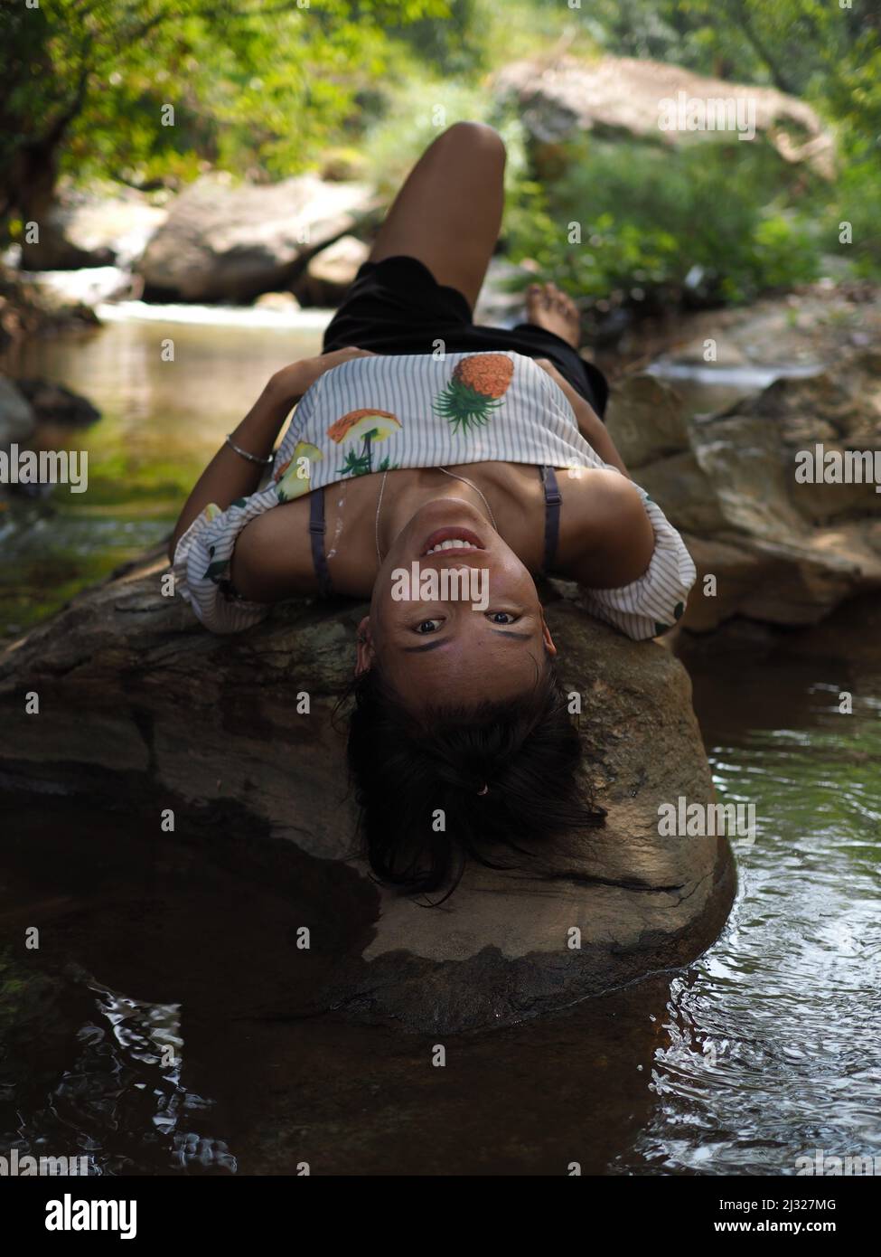 Junge asiatische Frau in einem Dschungelfluss in moderner Kleidung Stockfoto