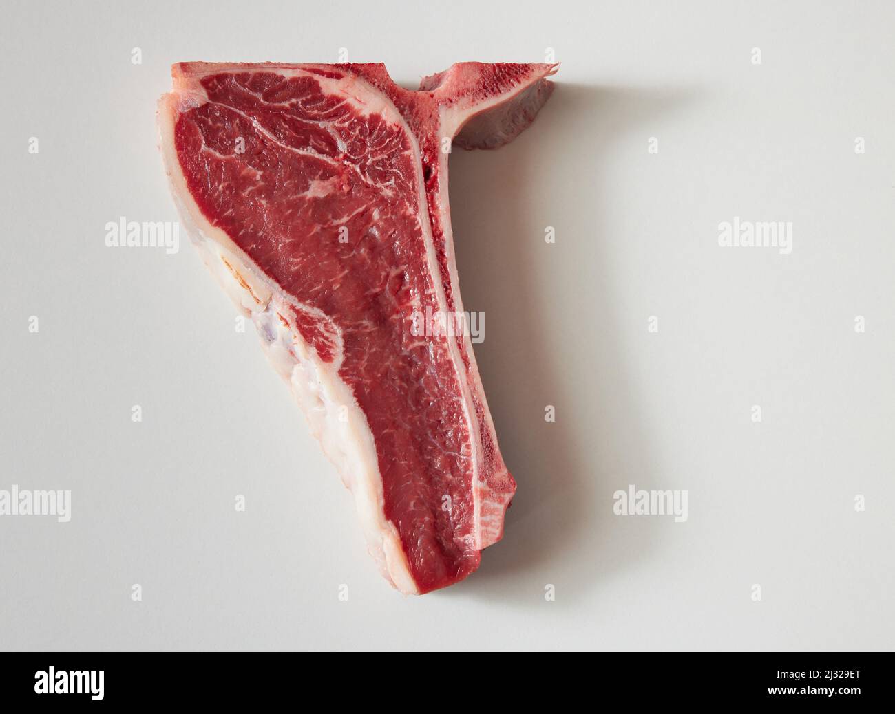 Draufsicht auf ein halbes T-Bone-Steak für die Ernährung, weniger Fleisch essen, den Planeten schützen und keine Fleischkonzepte. Stockfoto
