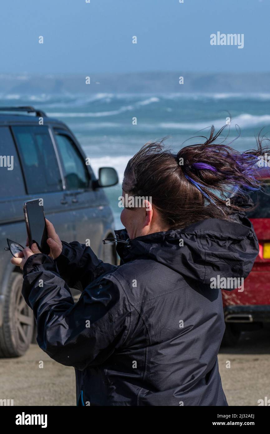Eine Frau, die mit ihrem Mobiltelefon die Sturmwetterbedingungen in Newquay in Cornwall fotografierte, als Sturm Eunice Großbritannien trifft. Stockfoto