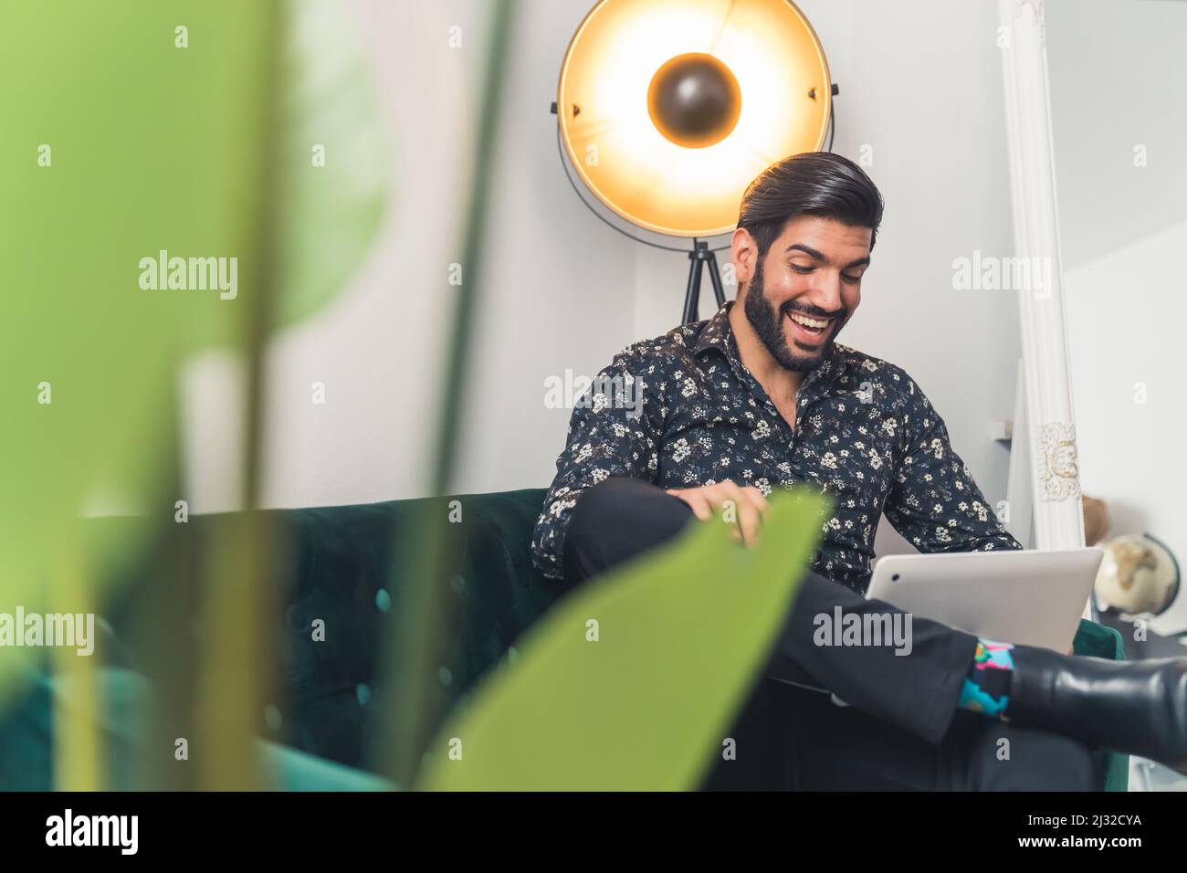 Gutaussehender lateinischer Mann, der per Videoanruf mit dem Laptop auf dem Sofa sitzt - Remote Meeting . Hochwertige Fotos Stockfoto