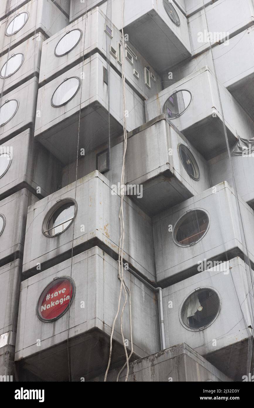 Ein Schild „Save Nakagin“, das in einem Fenster des Nakagin Capsule Tower Building, das von Kisho Kurokawa entworfen wurde (Beispiel des japanischen Stoffwechsels aus den Jahren 1970-1972), zu sehen ist, soll am 12. April 2022 abgerissen werden. Am 15. April 2007 stimmte eine Mehrheit der Kapselbesitzer für den Abriss des Turms, da er sich verschlechterte und Angst vor Asbest hatte, der im Bauprozess verwendet wurde. Es hat viele Versuche gegeben, das Gebäude zu retten, weil es aufgrund seines Designs, seiner Struktur und seiner Philosophie als einzigartig angesehen wird. (Foto von Stanislav Kogiku/SOPA Images/Sipa USA) Stockfoto