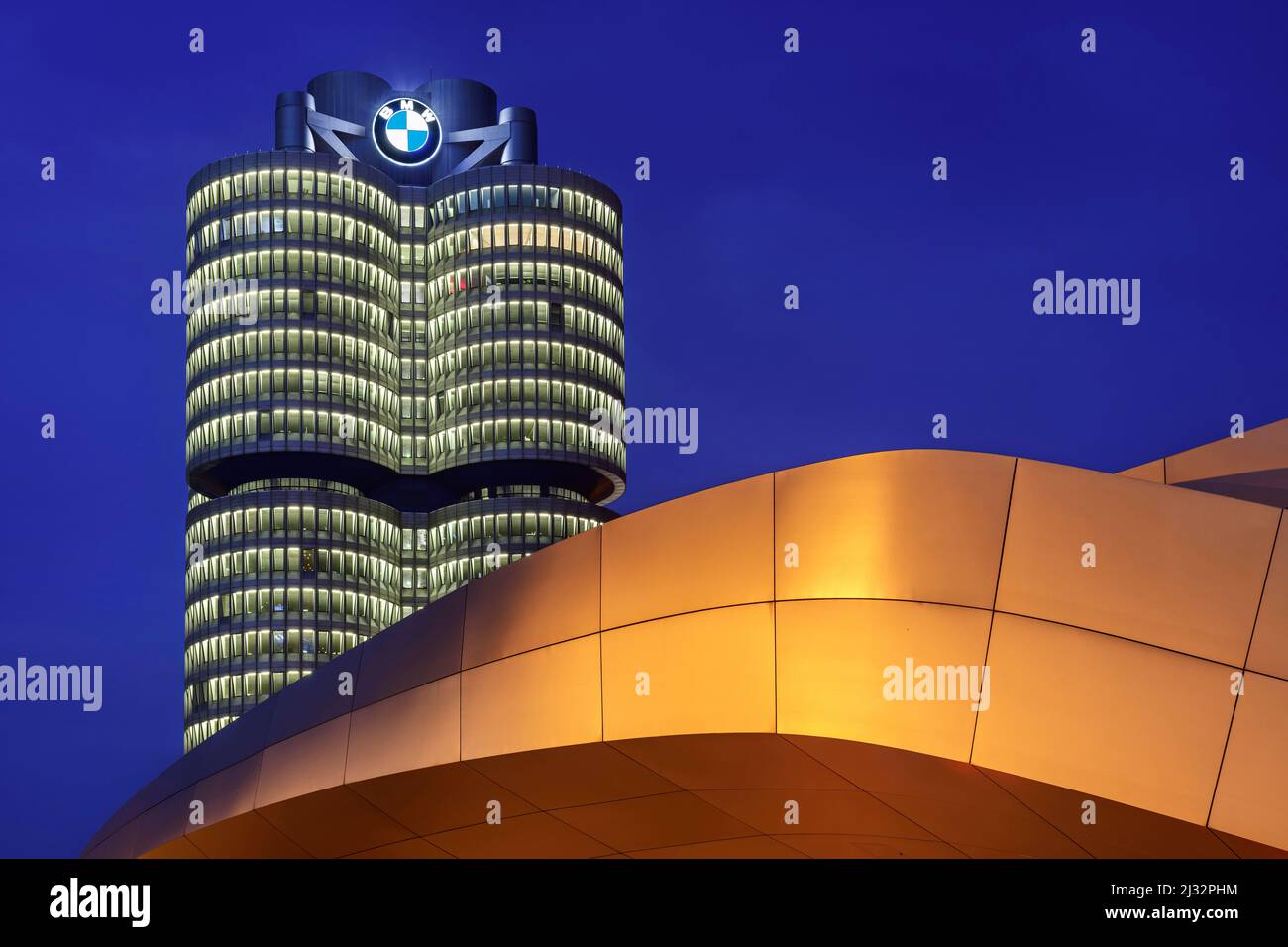 Gelb beleuchtetes BMW Welt Gebäude mit BMW Vierzylinder im Hintergrund, München, Oberbayern, Bayern, Deutschland Stockfoto