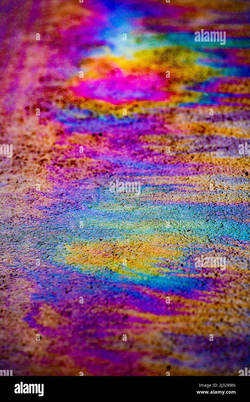 Viele Farben, die durch ein Ölleck auf nasser Straße entstehen. Stockfoto