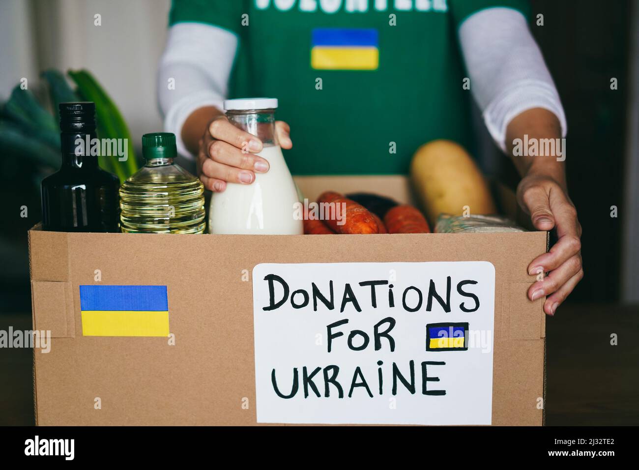 Freiwilliger bereitet Nahrungsmittelbox für ukrainische Kriegsflüchtlinge vor - Konzept für humanitäre Hilfe und Hilfe - Fokus auf rechte Haltebox Stockfoto