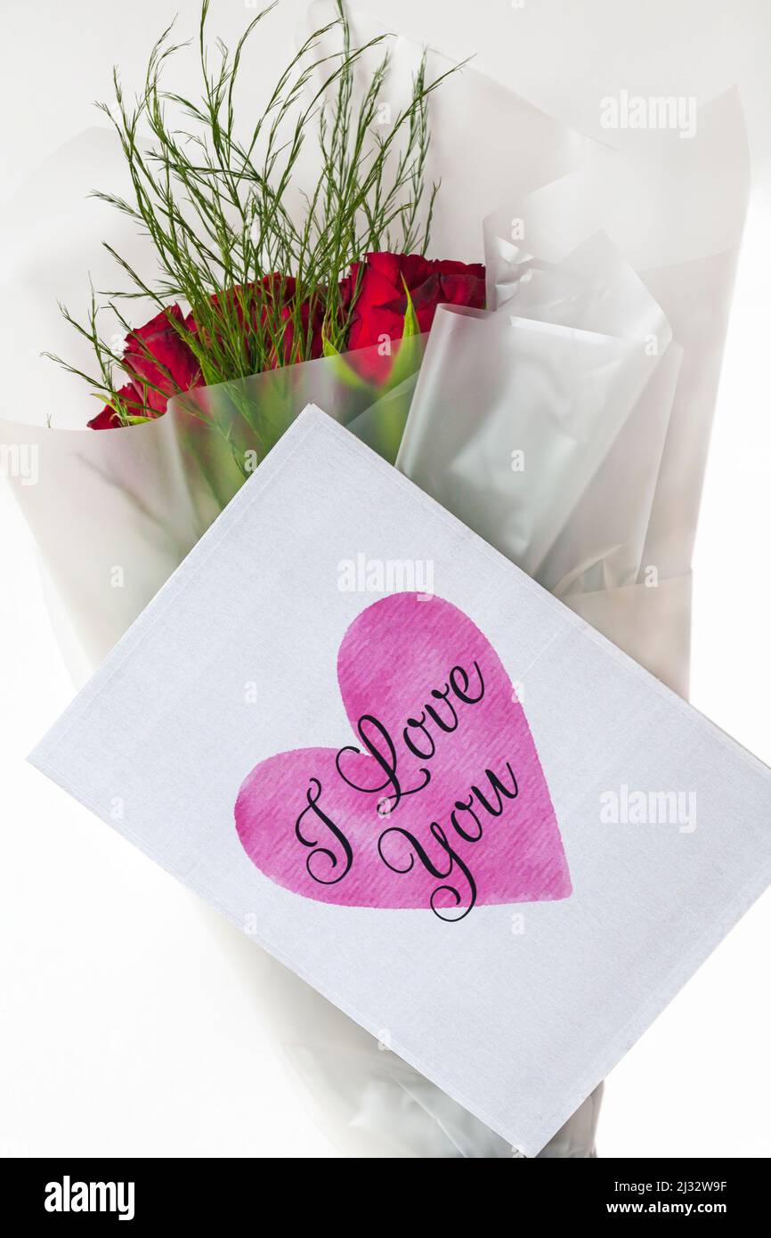 Ein Strauß roter Rosen mit „I Love You“ Valentinskarte für den Valentinstag auf weißem Hintergrund Stockfoto