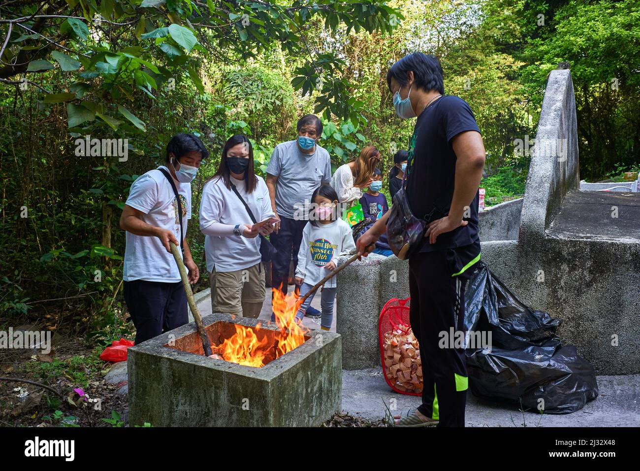 Hongkong, China. 05. April 2022. Eine Familie verbrennt Papiere in der Nähe eines Grabes auf einem chinesischen Hung Shui Kiu Friedhof in Hongkong, um die Vorfahren zu ehren. Chinesische Menschen besuchen Friedhofs, um ihre Vorfahren zu ehren, am "Grave Sweeping Day", dem Qing Ming Festival in Hongkong (Foto von Emmanuel Serna/SOPA Images/Sipa USA) Quelle: SIPA USA/Alamy Live News Stockfoto