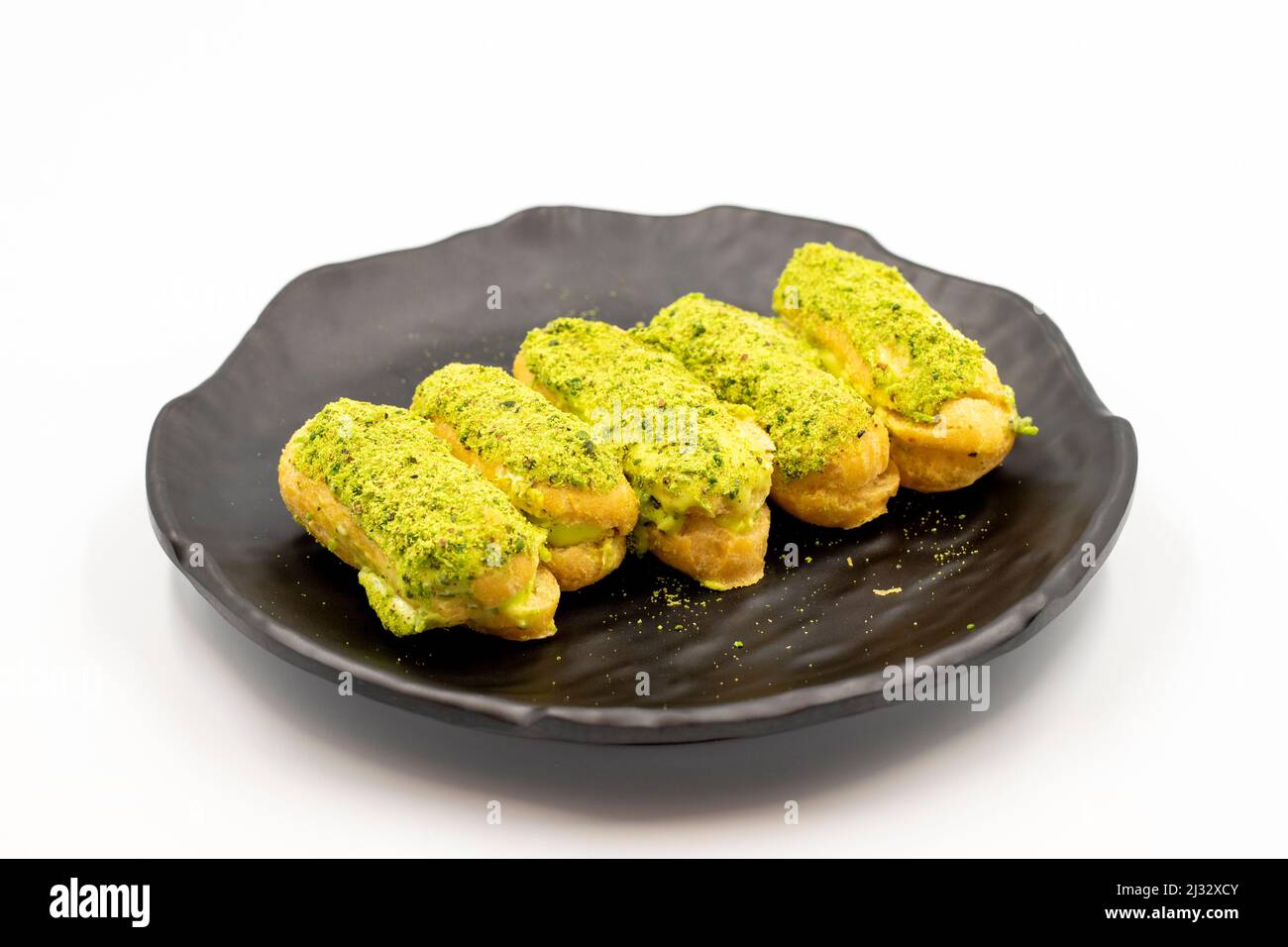 Pistazie eclair Kuchen isoliert auf weißem Hintergrund. Köstlichkeiten der Weltküche. Nahaufnahme Stockfoto