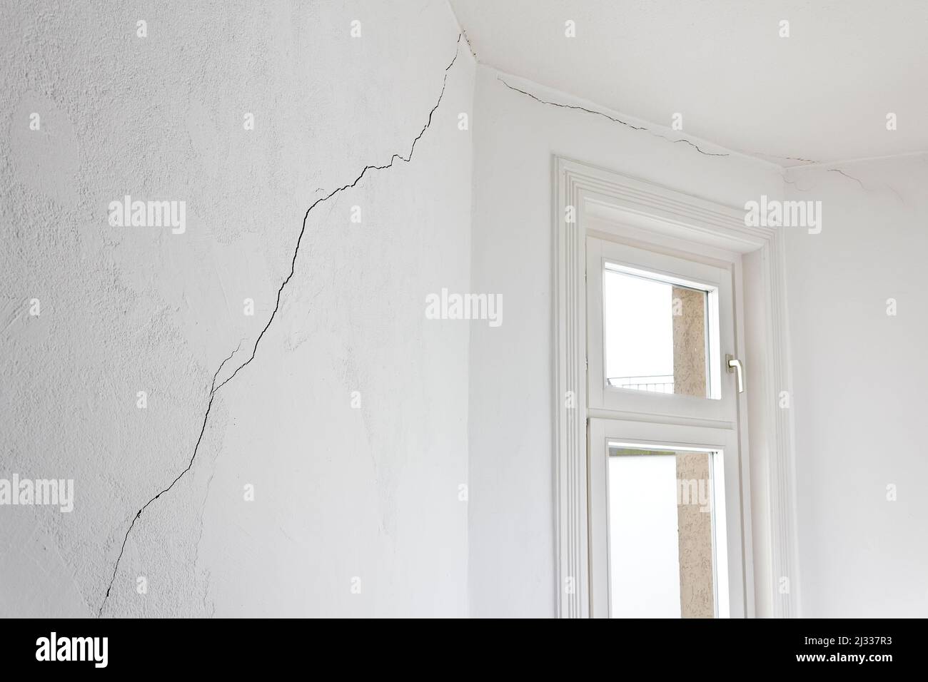 Gebäudeschadenkonzept: Sehr langer Riss in der Wand einer Wohnung oder Wohnung in einem alten Haus, verursacht durch ein Erdbeben oder Erdrutsch. Stockfoto