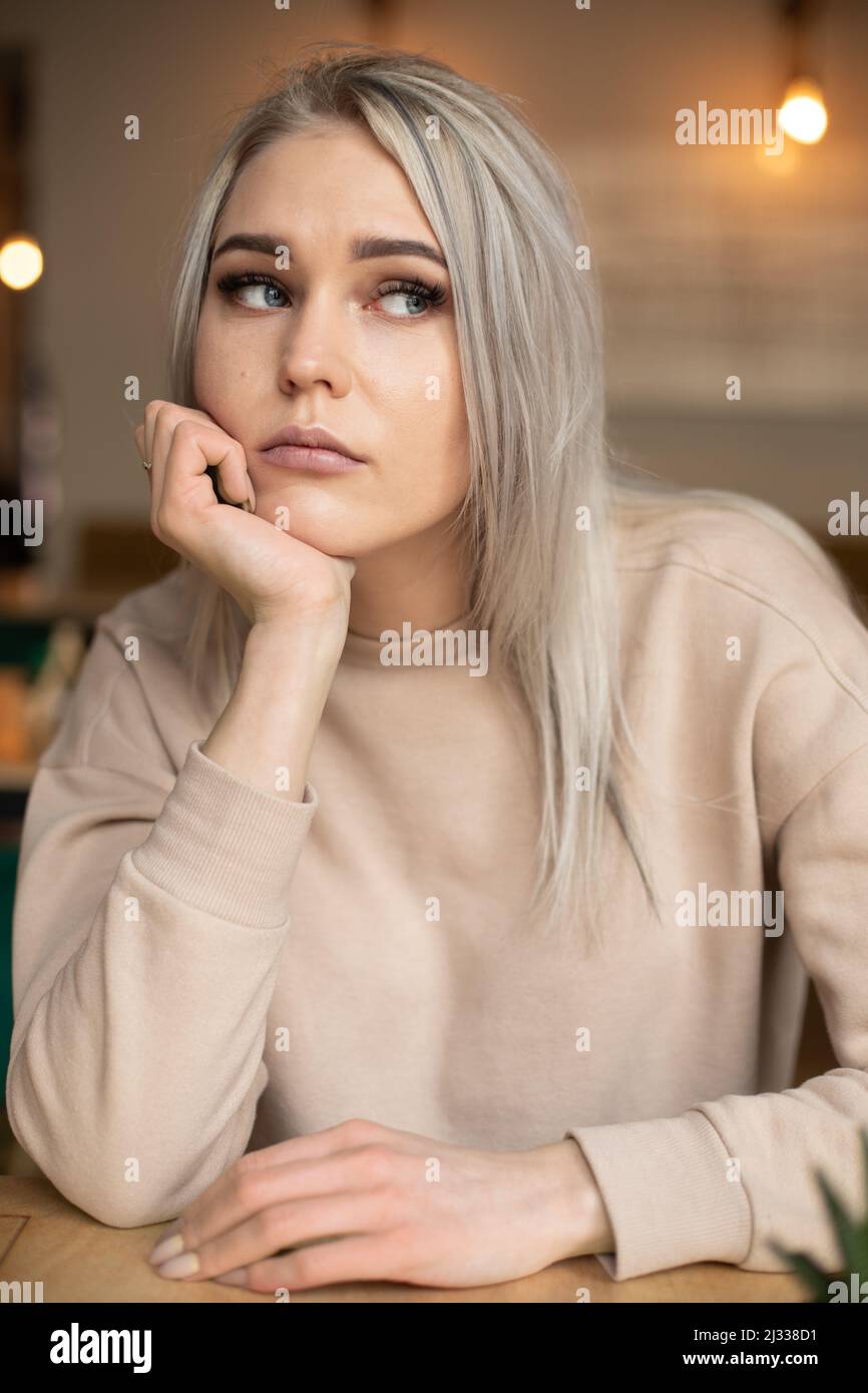 Porträt einer jungen attraktiven nachdenklichen Frau mit langen grauen Haaren mit niedlichen professionellen Make-up ruht Kinn auf der Hand. Stockfoto