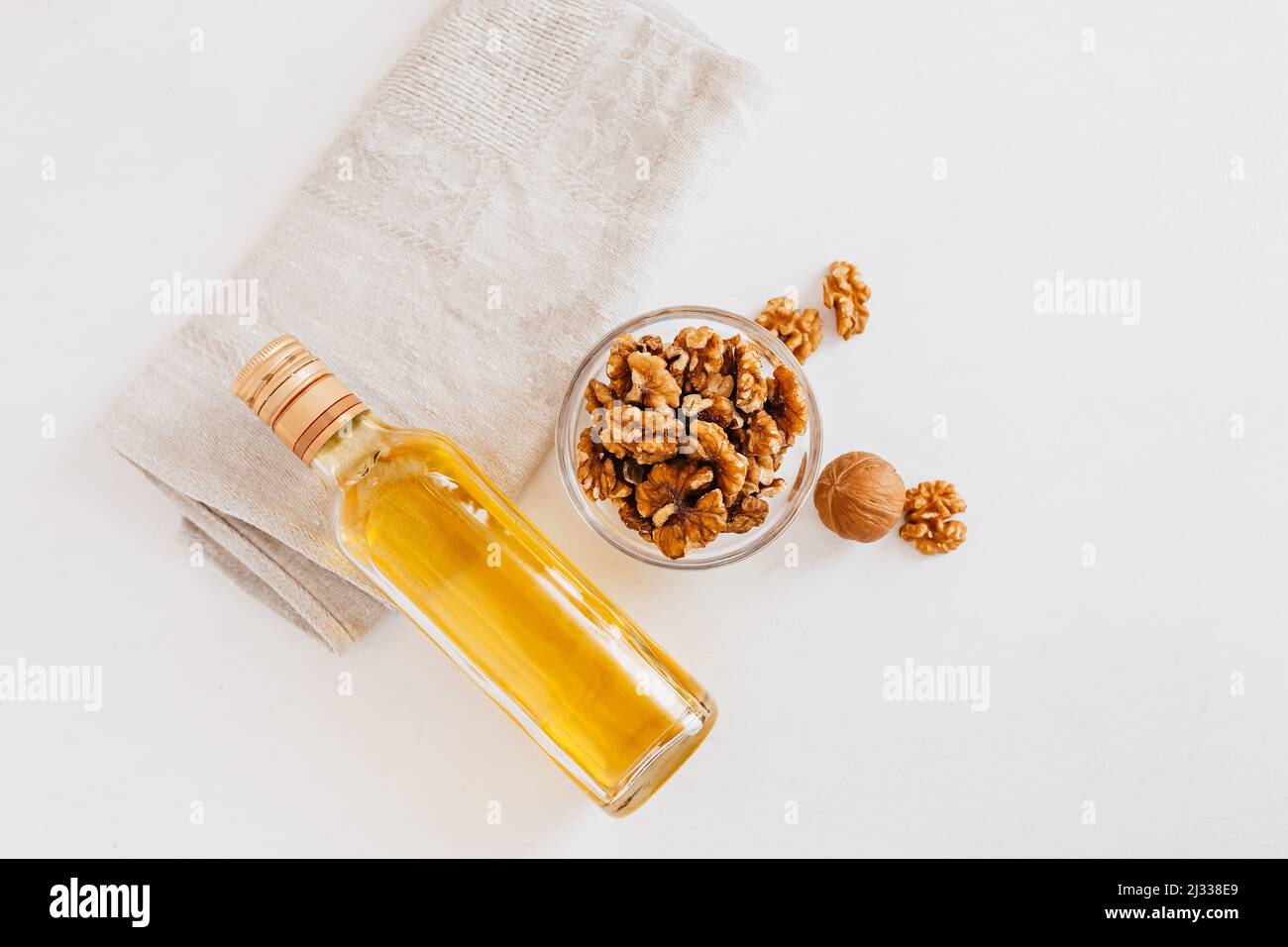 Walnuss oder Olivenöl in Glas Flasche, ganze große geschälte Walnusskern mit dünner Schale auf weißem Hintergrund. Gesunde Ernährung für das Gehirn. Frische Walnüsse zurück Stockfoto