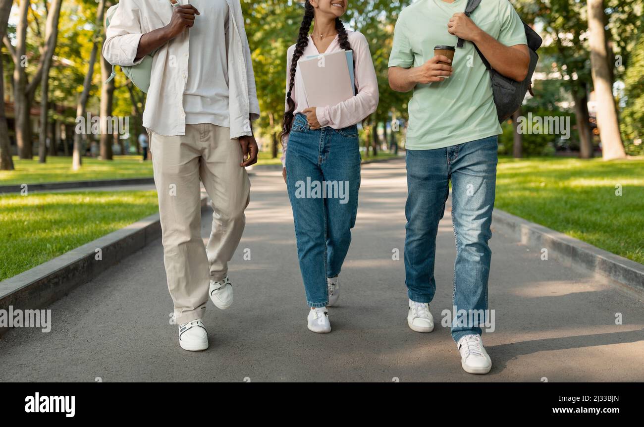 Nicht wiedererkennbare, vielfältige Jugendliche Studenten, die nach dem Unterricht auf dem College-Campus spazieren, gemeinsam im Freien spazieren und reden Stockfoto