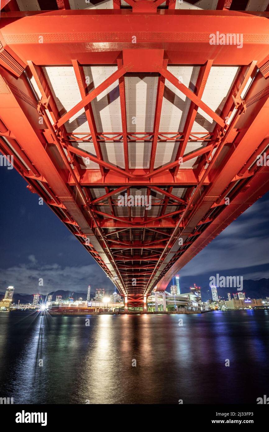 Eine vertikale Aufnahme der berühmten historischen Kobe-Brücke bei Nacht mit Stadtlichtern in Japan Stockfoto