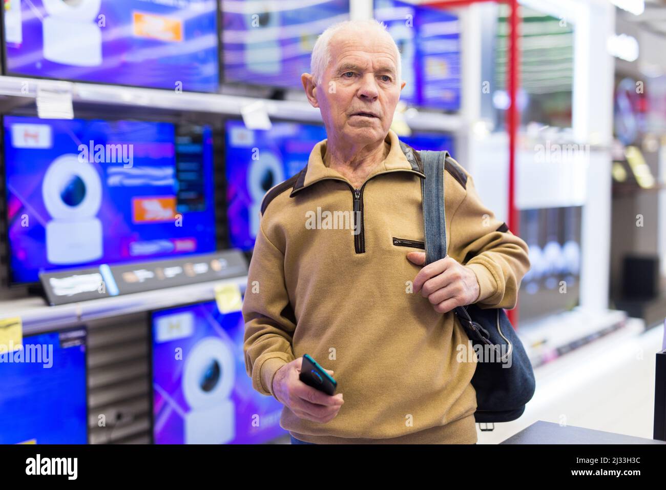 senor Mann Rentner kaufen modernen digitalen Fernseher mit Smart-tv im Showroom der digitalen elektronischen Warenhaus Stockfoto