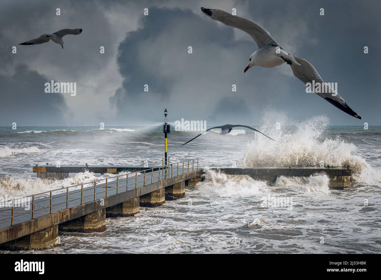 Stürmische Meereswellen, die während eines Winters über einem Pier plantschen Stockfoto