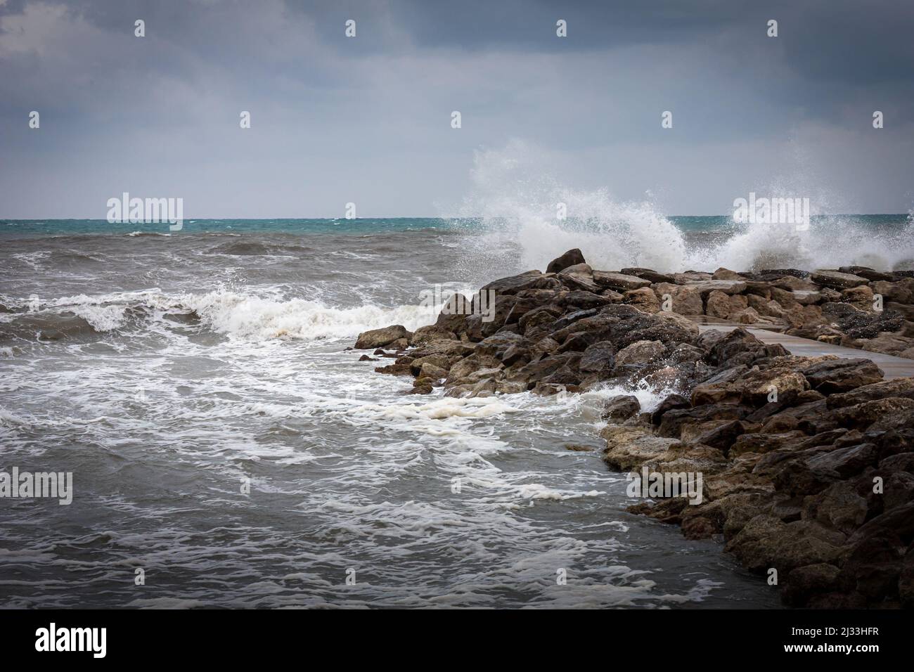 An einem stürmischen Tag winkt das Meer gegen eine felsige Küste. Stockfoto