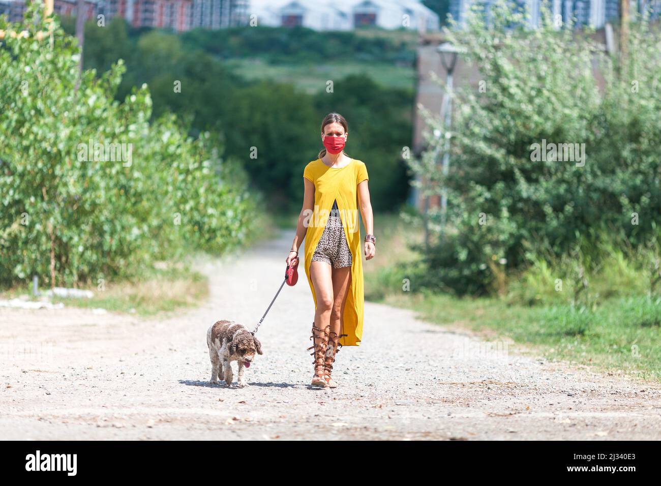 Junge Frau, die auf der Straße spazieren geht, während sie eine Gesichtsmaske trägt Stockfoto