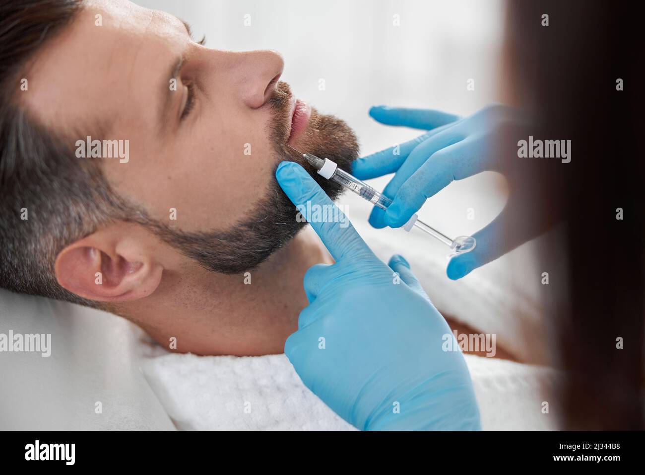 Kosmetikerin macht Füller Injektion an Person mittleren Alters bei Lippenvergrößerung Verfahren in der Klinik Stockfoto