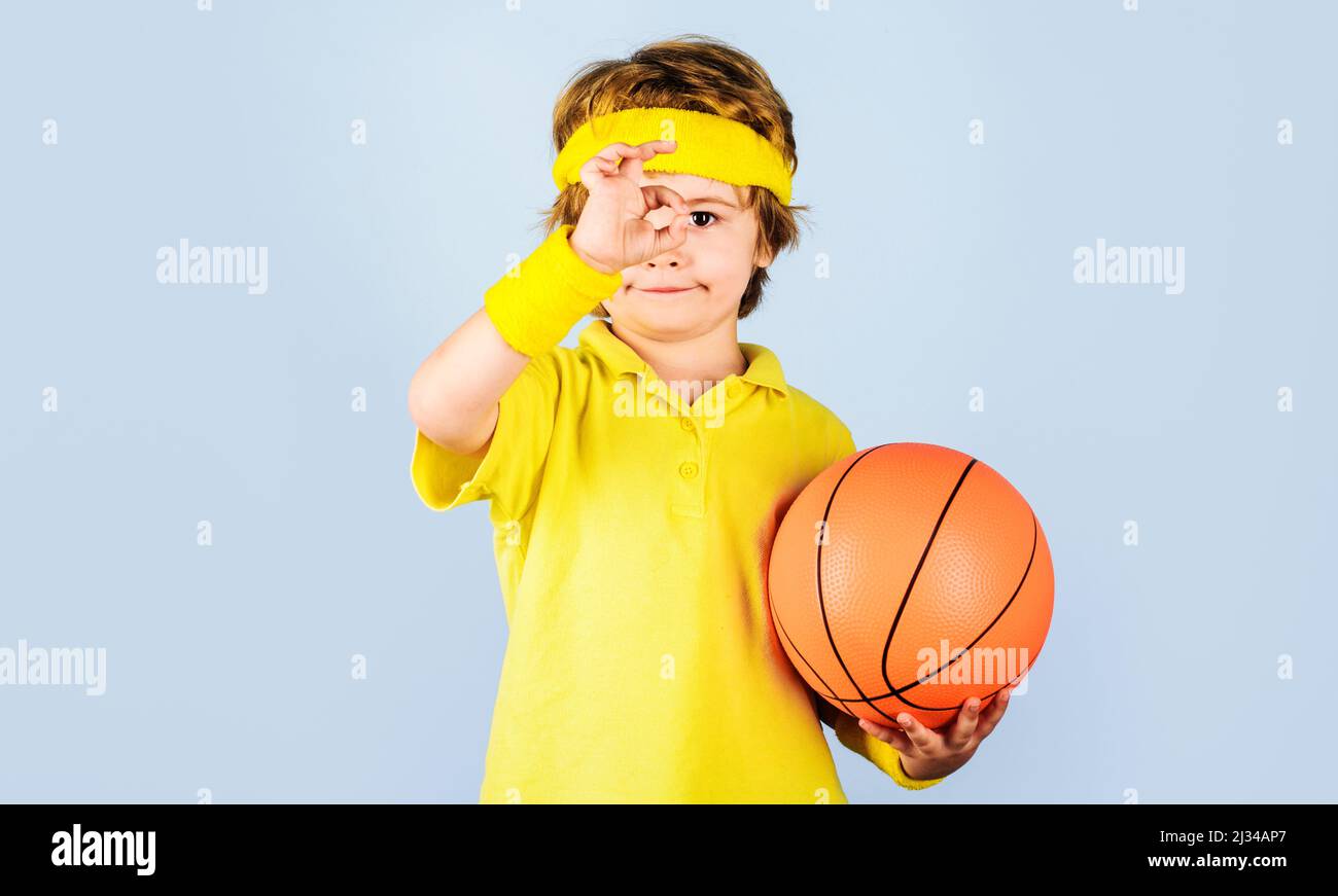 Sportlicher Junge mit Basketballball, der ein Zeichen für die Ordnung zeigt. Sport für Kinder. Kleiner Basketballspieler. Stockfoto