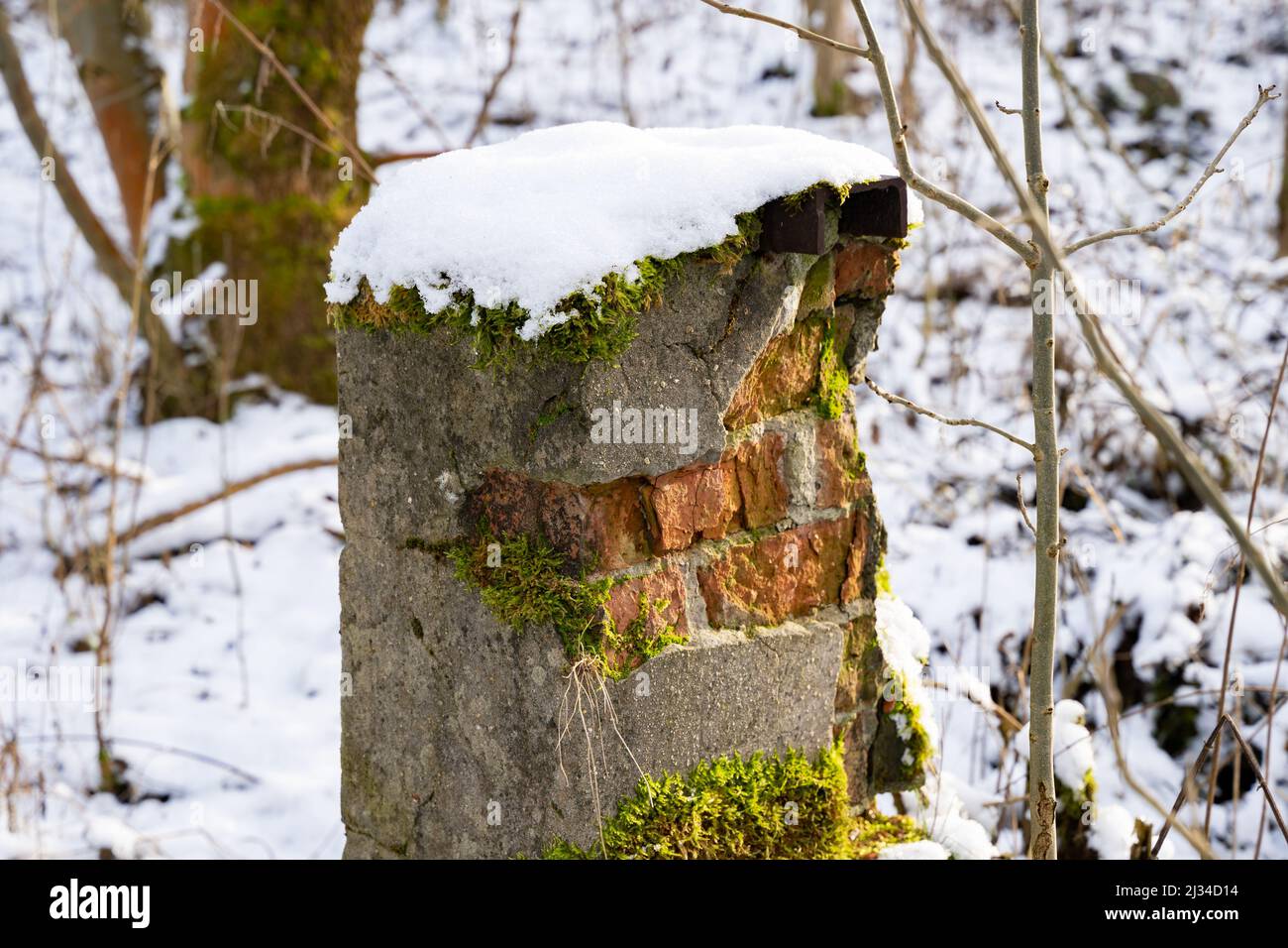 Verwitterte Säule mit Schnee und gebrochenem Äußeren. Alte ländliche Gegend mit verlassenen Gebäuden. Erosion durch Wetter, Wind und Temperatur. Stockfoto