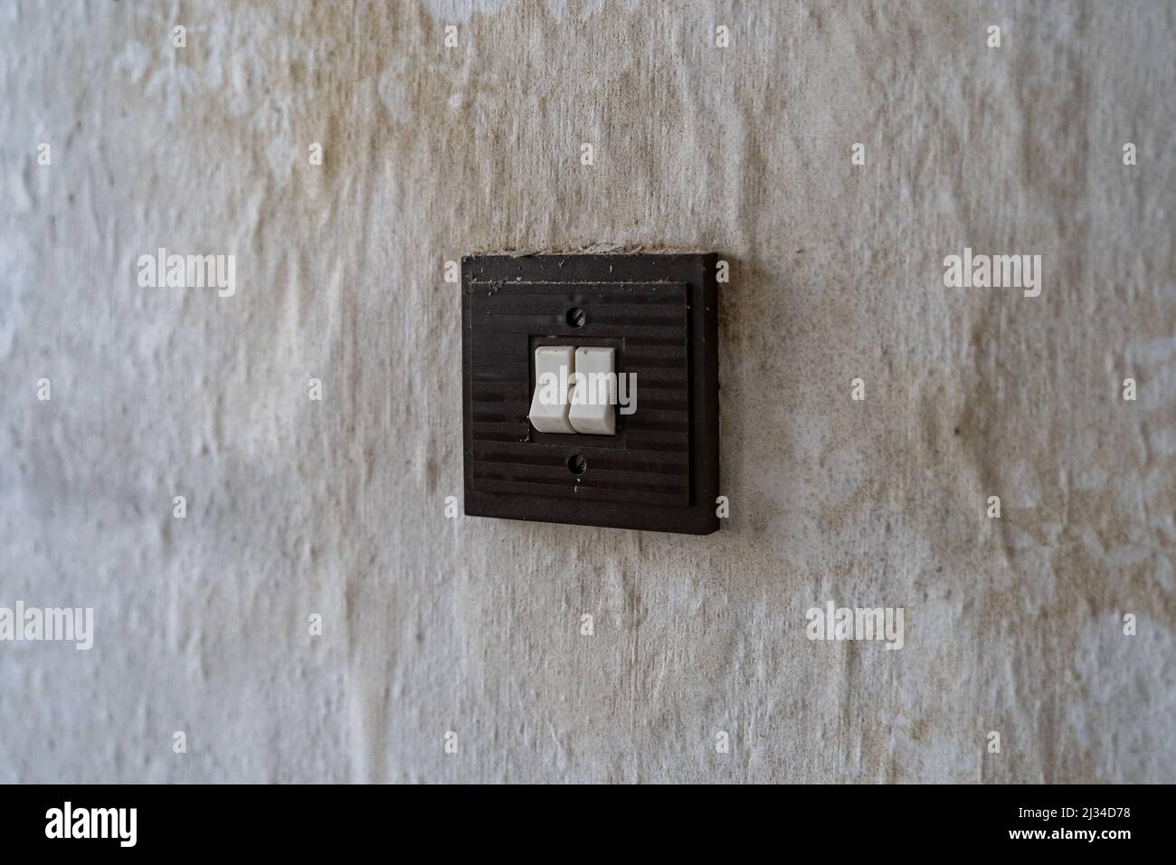 Dreckiger alter quadratischer Lichtschalter an einer Wand. Retro-Kippschalter in einer ostdeutschen Wohnung. Innenarchitektur der Vergangenheit in einem schlechten Zustand. Schmutzflecken Stockfoto