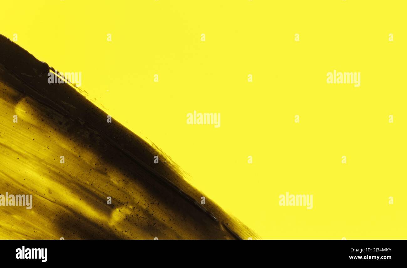 Abstrakte schwarze Abstriche (Holzkohle-Zahnpasta) auf gelbem Hintergrund, Platz für Text rechts Stockfoto