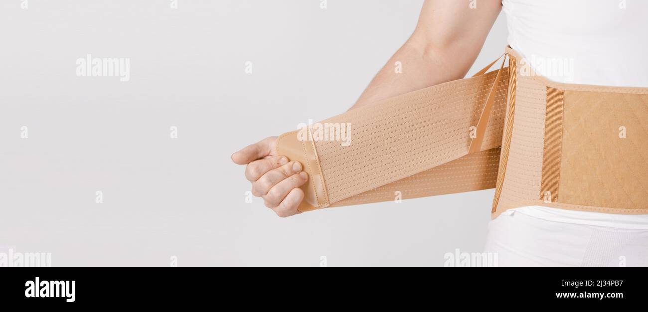 Lendenwirbelstütze am menschlichen Körper isoliert auf weißem Hintergrund. Trauma des Rückens. Rückenstütze, orthopädische Lendenwirbelstütze, Stützgurt für die Rückenmuskulatur. Senken Stockfoto
