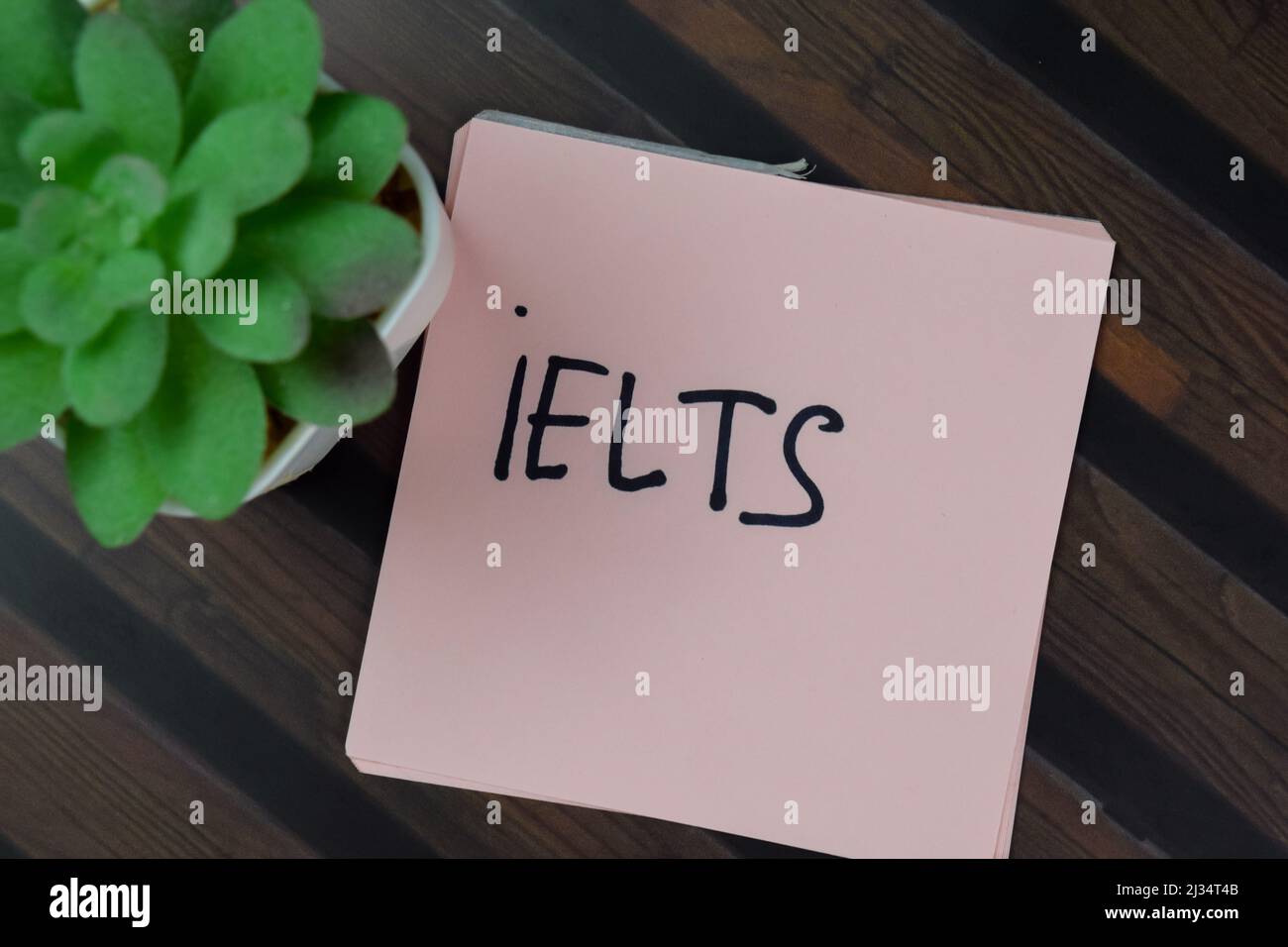 IELTS schreiben auf Haftnotizen isoliert auf Holztisch. Stockfoto