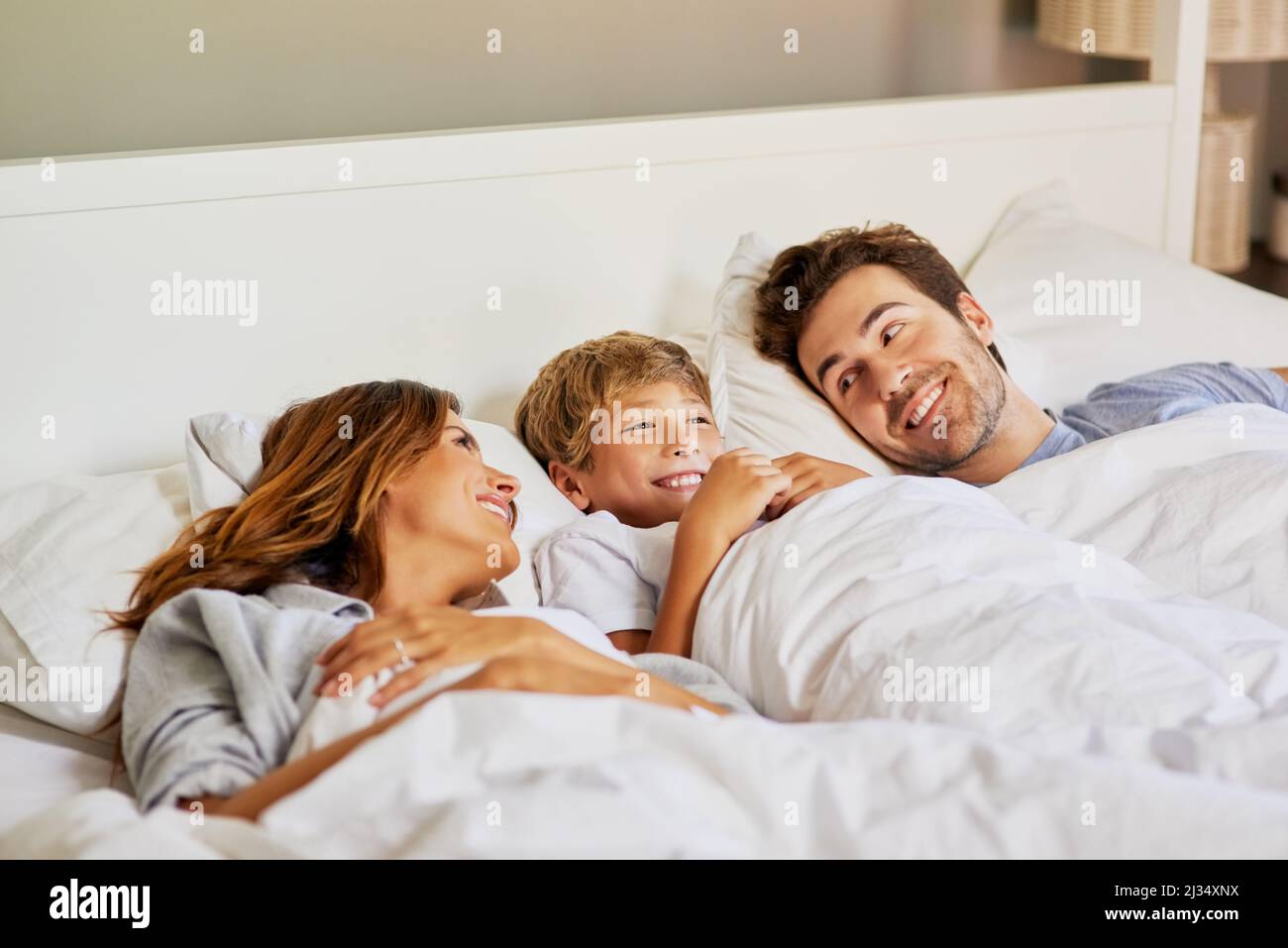 Zeit für die Familie am Morgen. Aufnahme einer fröhlichen jungen Familie, die tagsüber im Bett zu Hause relaxt. Stockfoto