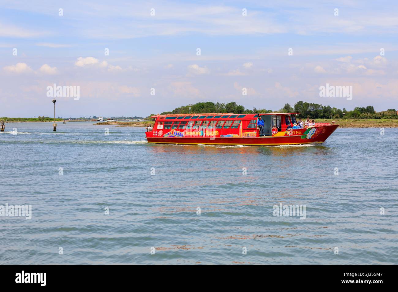 Blick von Burano auf Torcello, kleine Inseln in der Lagune von Venedig, auf ein rotes Ausflugsboot, Venedig, Italien Stockfoto