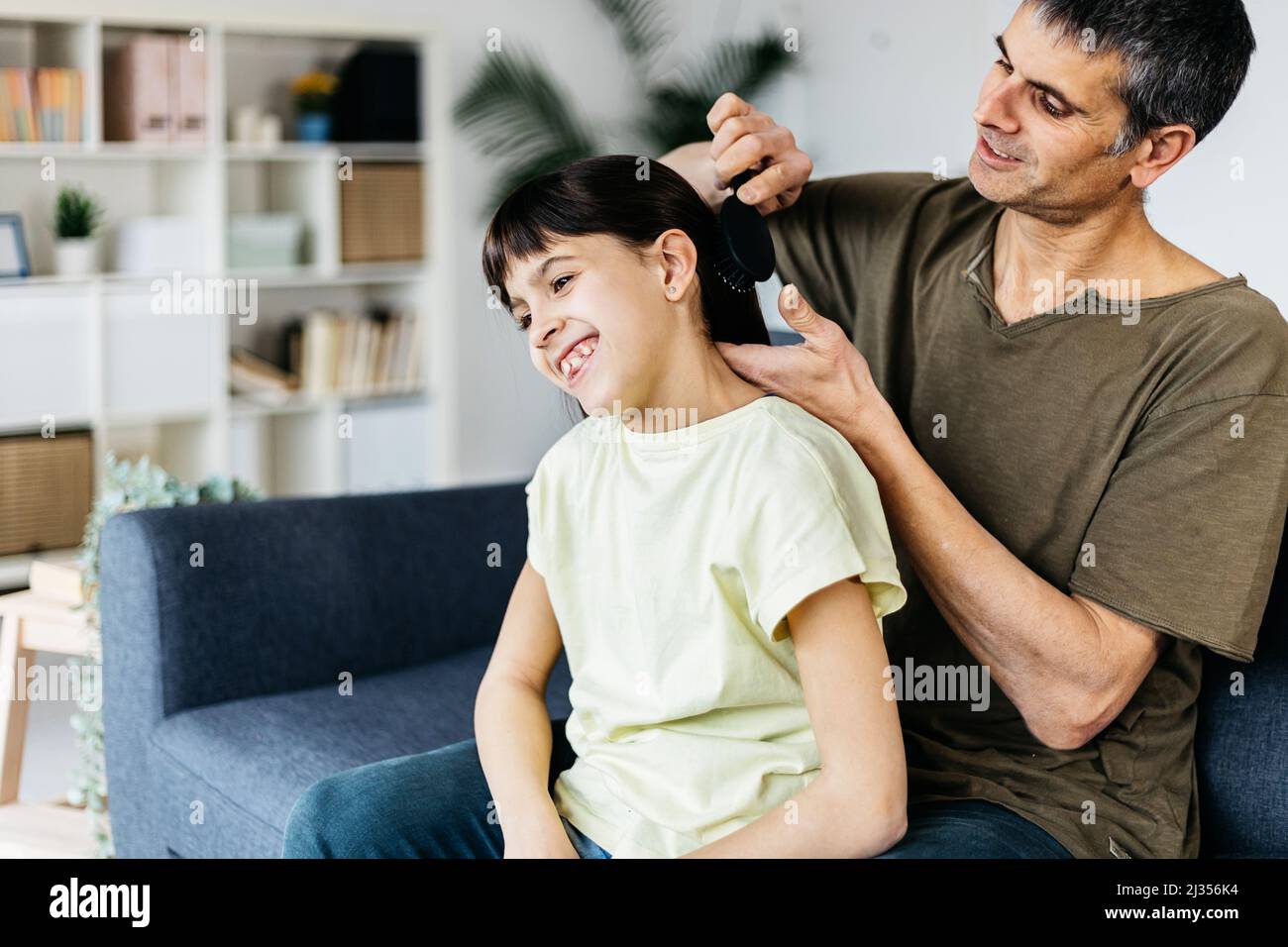 Fürsorglicher Vater, der seiner Tochter zu Hause Haare putzt. Stockfoto